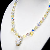 Angled close-up of Golden Star Cat Charm Necklace showing pale yellow crystals, iridescent star beads and a white cat with a gold star.