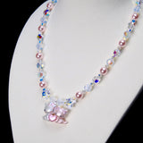 Angled close-up of Sweethearts Cat Duo Necklace showing two cat figures with a pink heart, pink pearls and iridescent crystals.