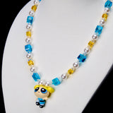 Angled close-up of Blue Dreamer Charm Necklace showing the blue-outfit girl pendant, aqua crystals and white pearls.