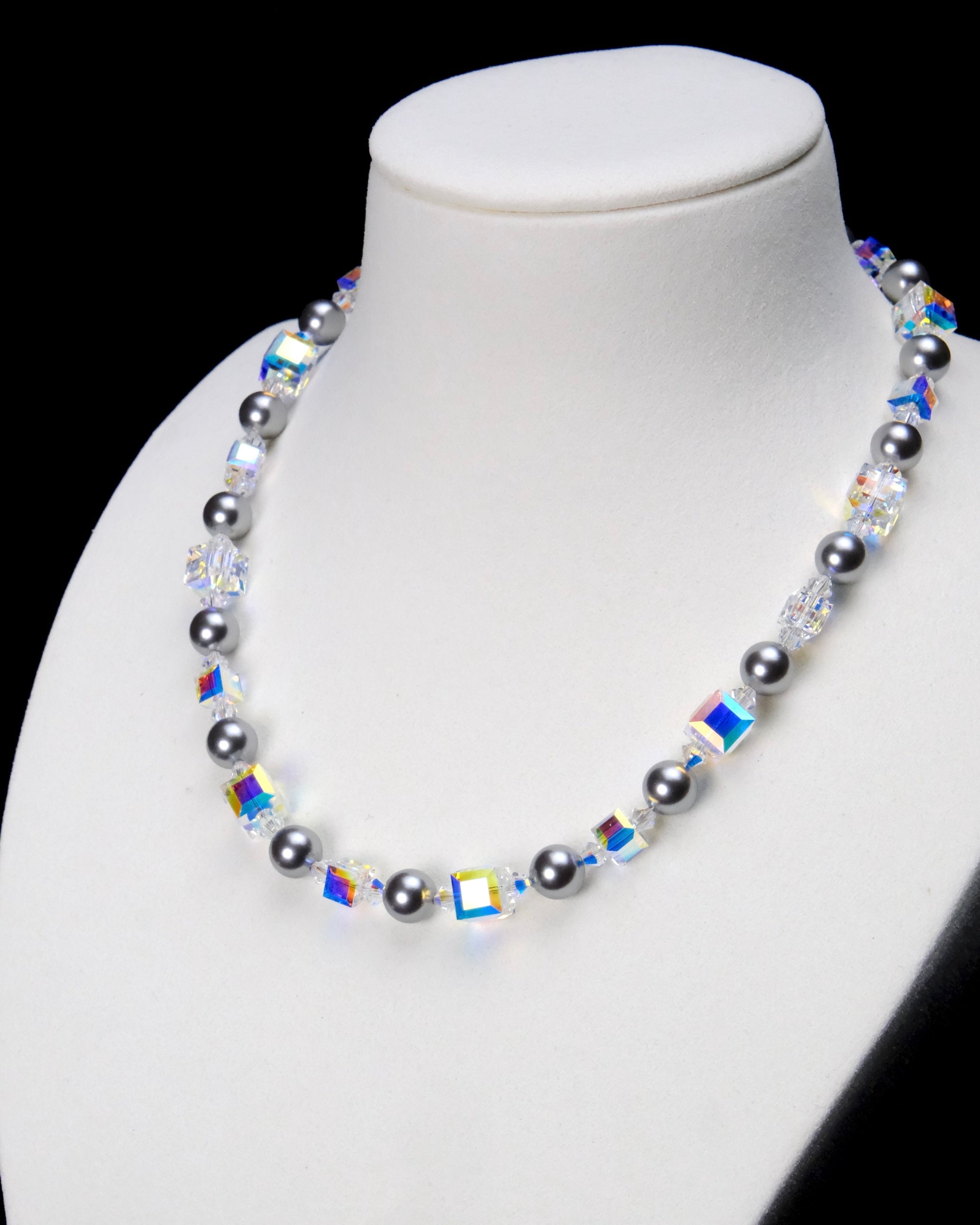 Angled close-up of Midnight Prism Pearl Choker showing dark gray pearls and rainbow-reflective crystal cubes.