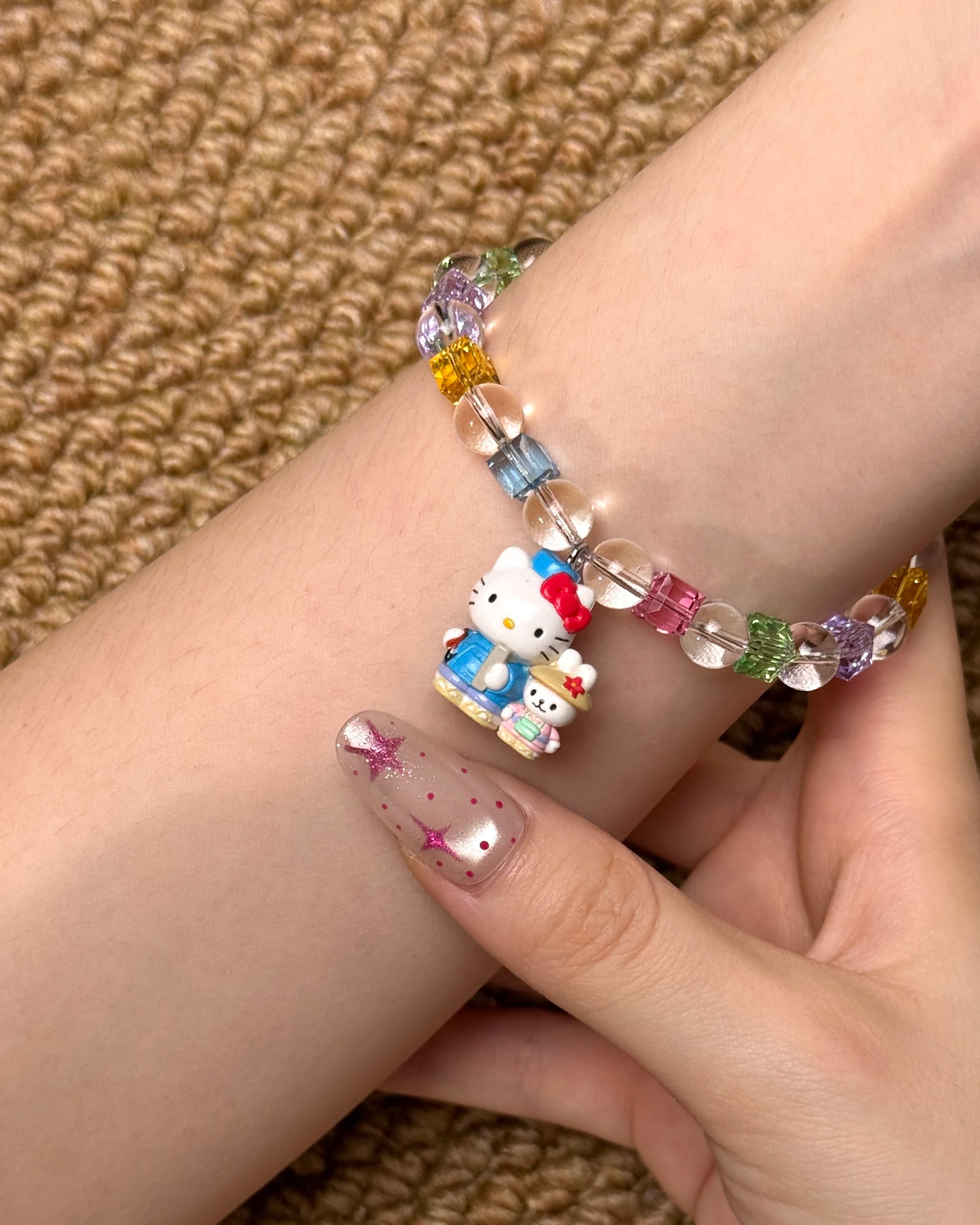 Angled studio product view of Rainbow Friends Crystal Charm Bracelet on a white jewelry display against a black background.