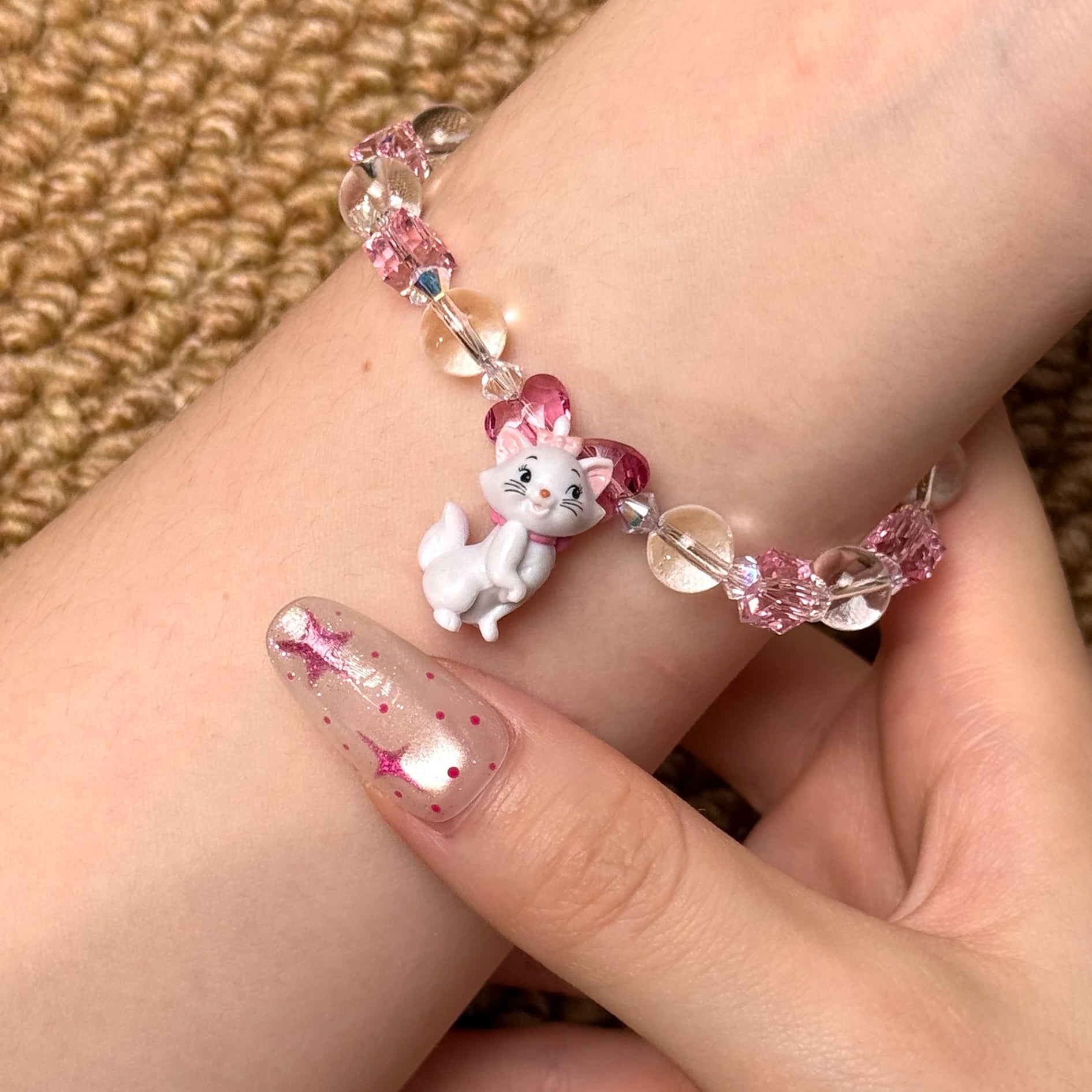 Angled studio product view of Pink Bow Crystal Charm Bracelet on a white jewelry display against a black background.
