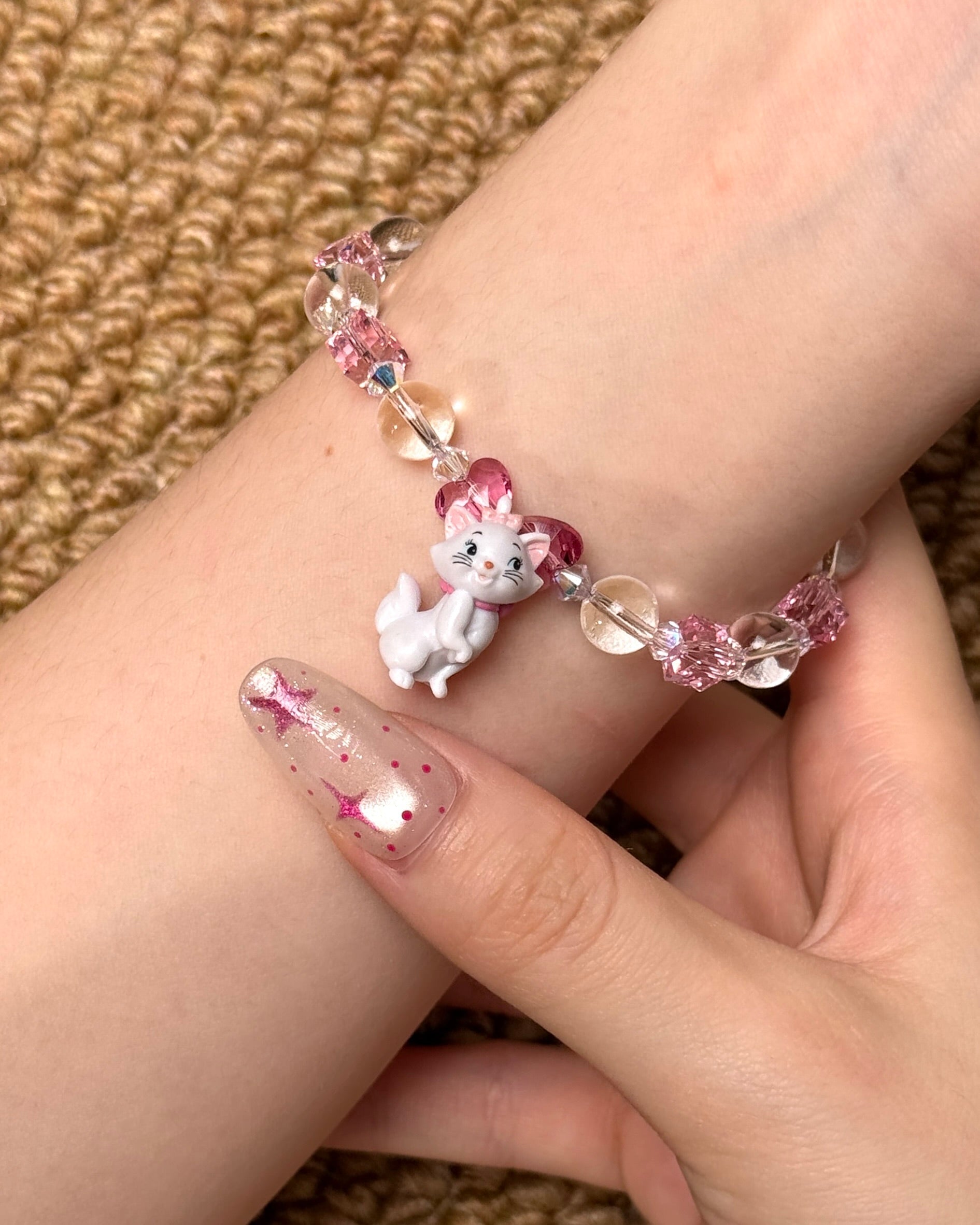 Angled studio product view of Pink Bow Crystal Charm Bracelet on a white jewelry display against a black background.