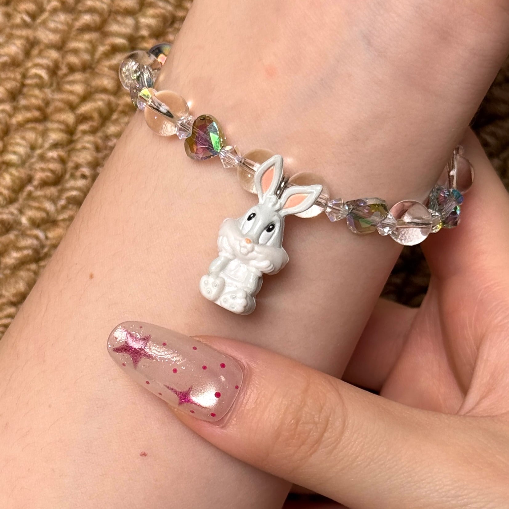 Angled studio product view of Iridescent Bunny Crystal Charm Bracelet on a white jewelry display against a black background.