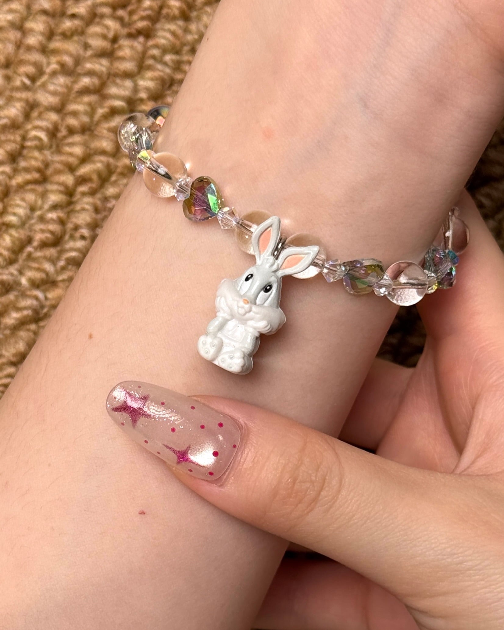 Angled studio product view of Iridescent Bunny Crystal Charm Bracelet on a white jewelry display against a black background.