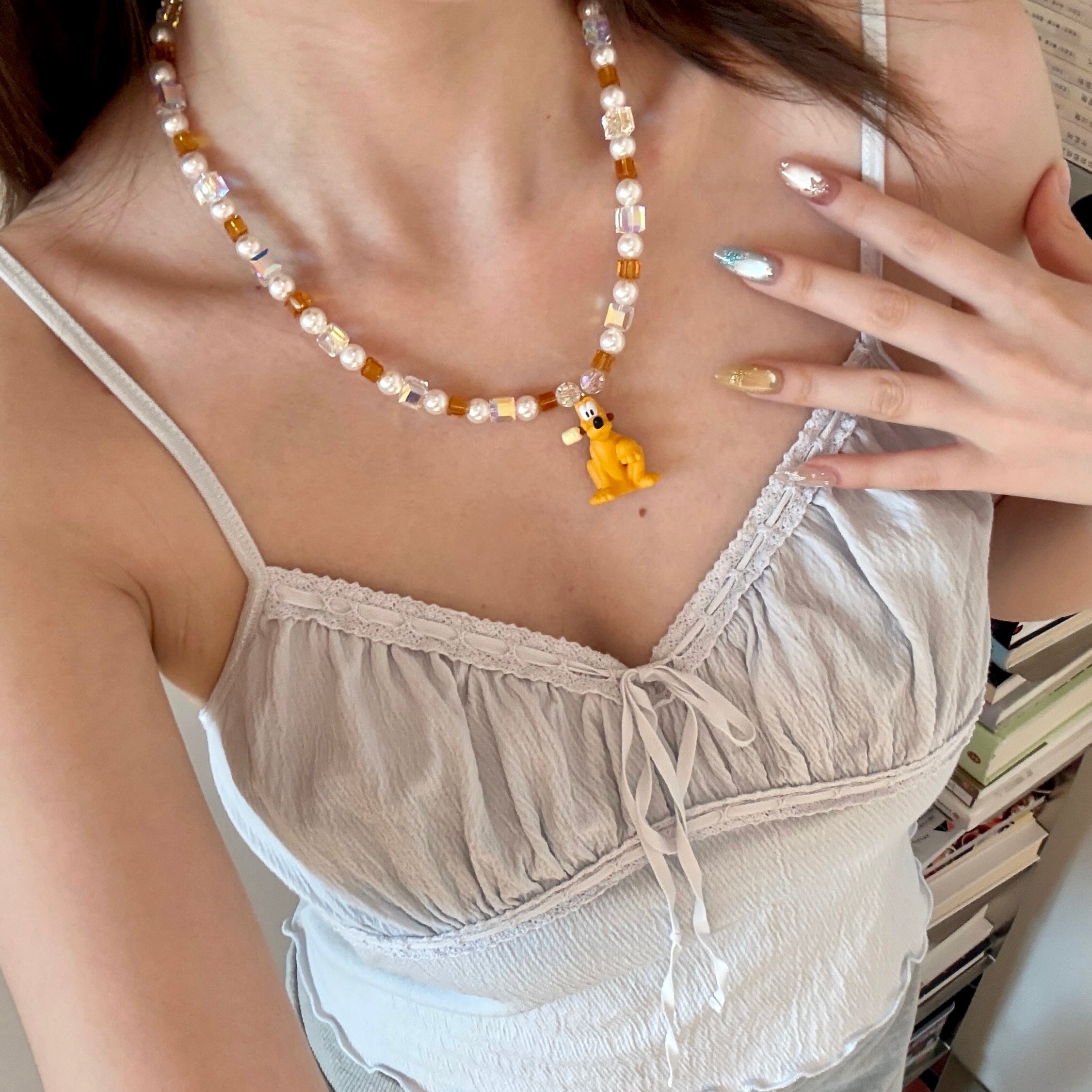 Close-up product image of Amber Daydream Crystal Charm Necklace featuring amber crystal cubes, pearly beads and dog character charm.