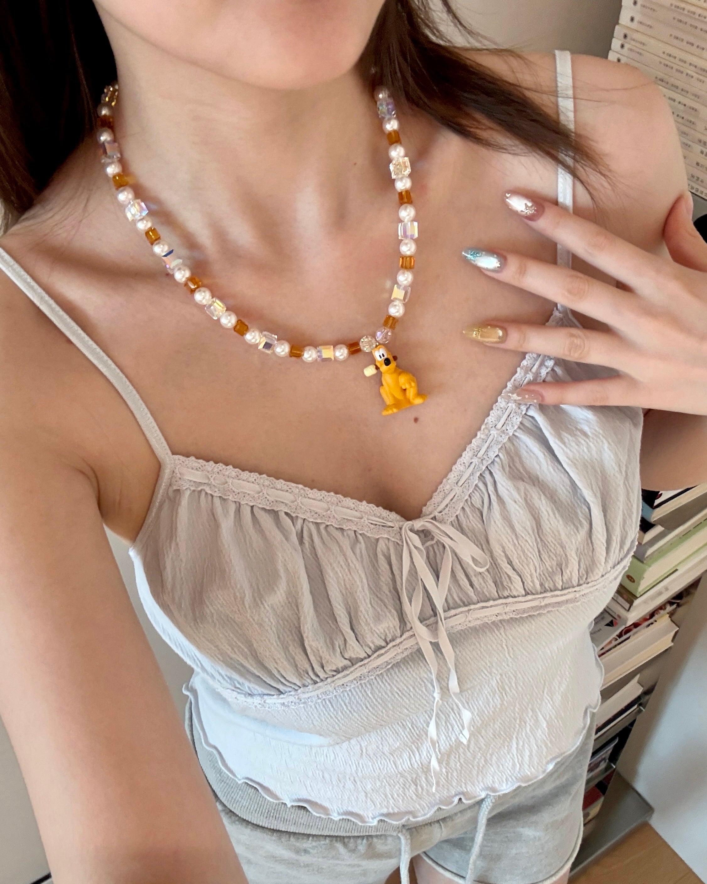 Close-up product image of Amber Daydream Crystal Charm Necklace featuring amber crystal cubes, pearly beads and dog character charm.