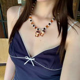 Model wearing a handmade colorful Swarovski crystal charm necklace with pearls and vintage-inspired charm details.