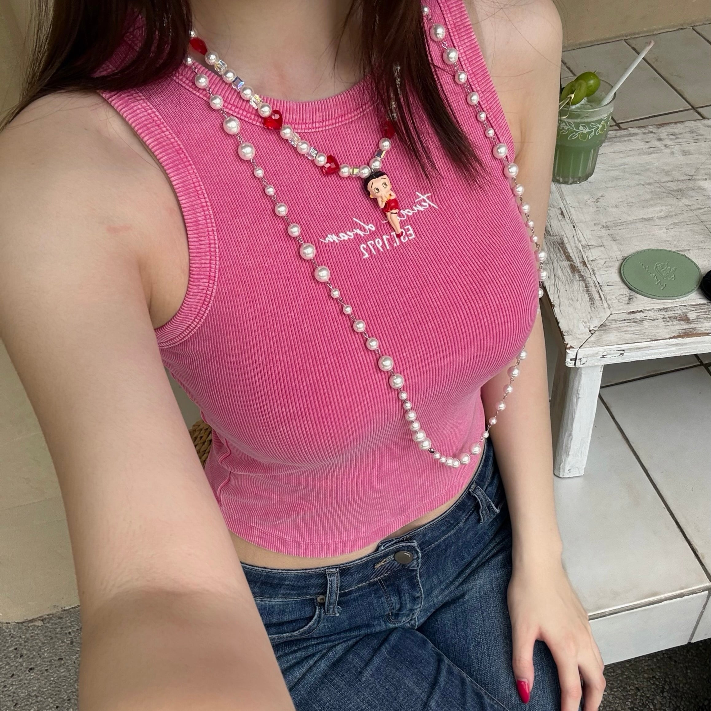 Model wearing a handmade red heart charm necklace with white Swarovski crystal pearls and iridescent cube beads.