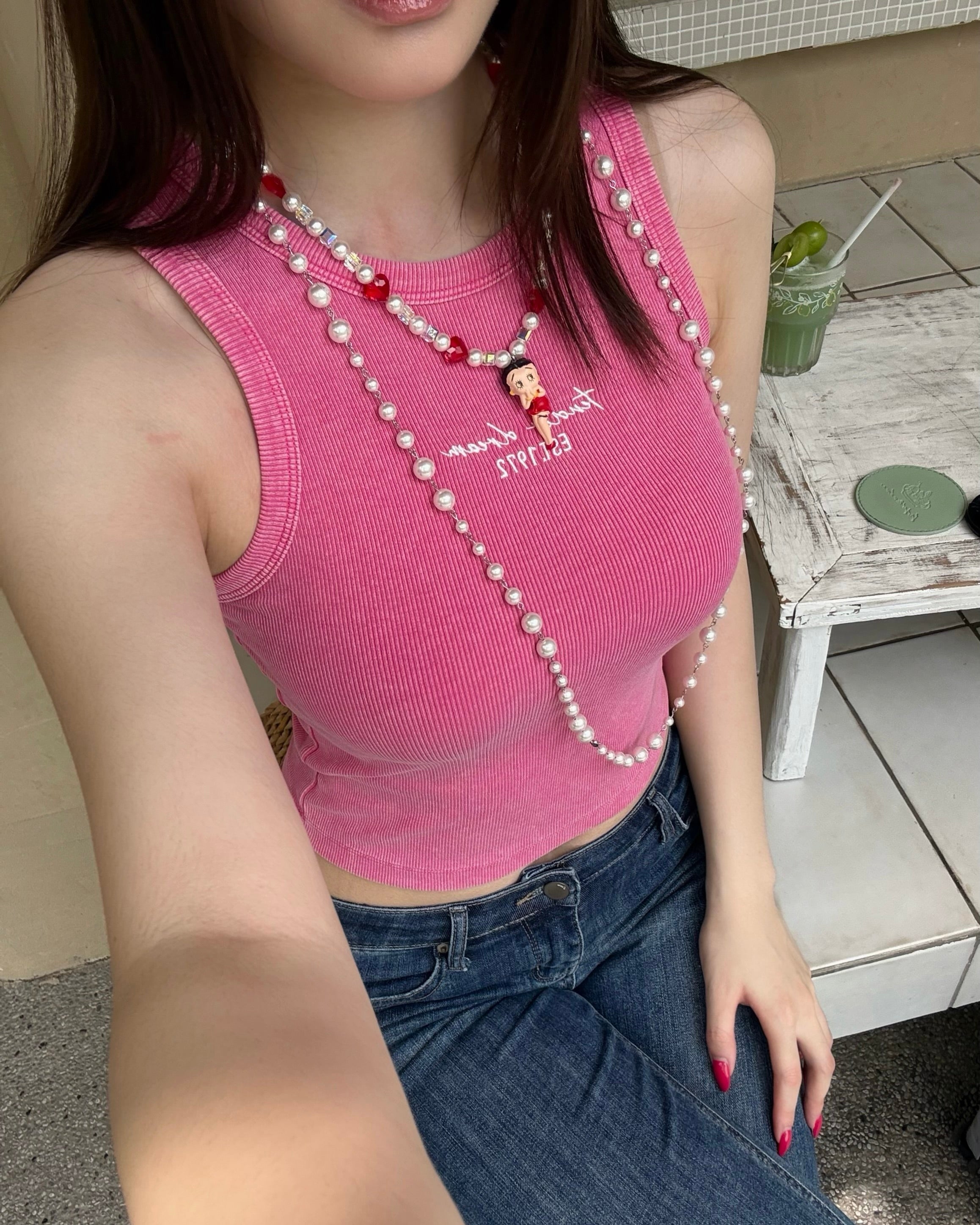 Model wearing a handmade red heart charm necklace with white Swarovski crystal pearls and iridescent cube beads.