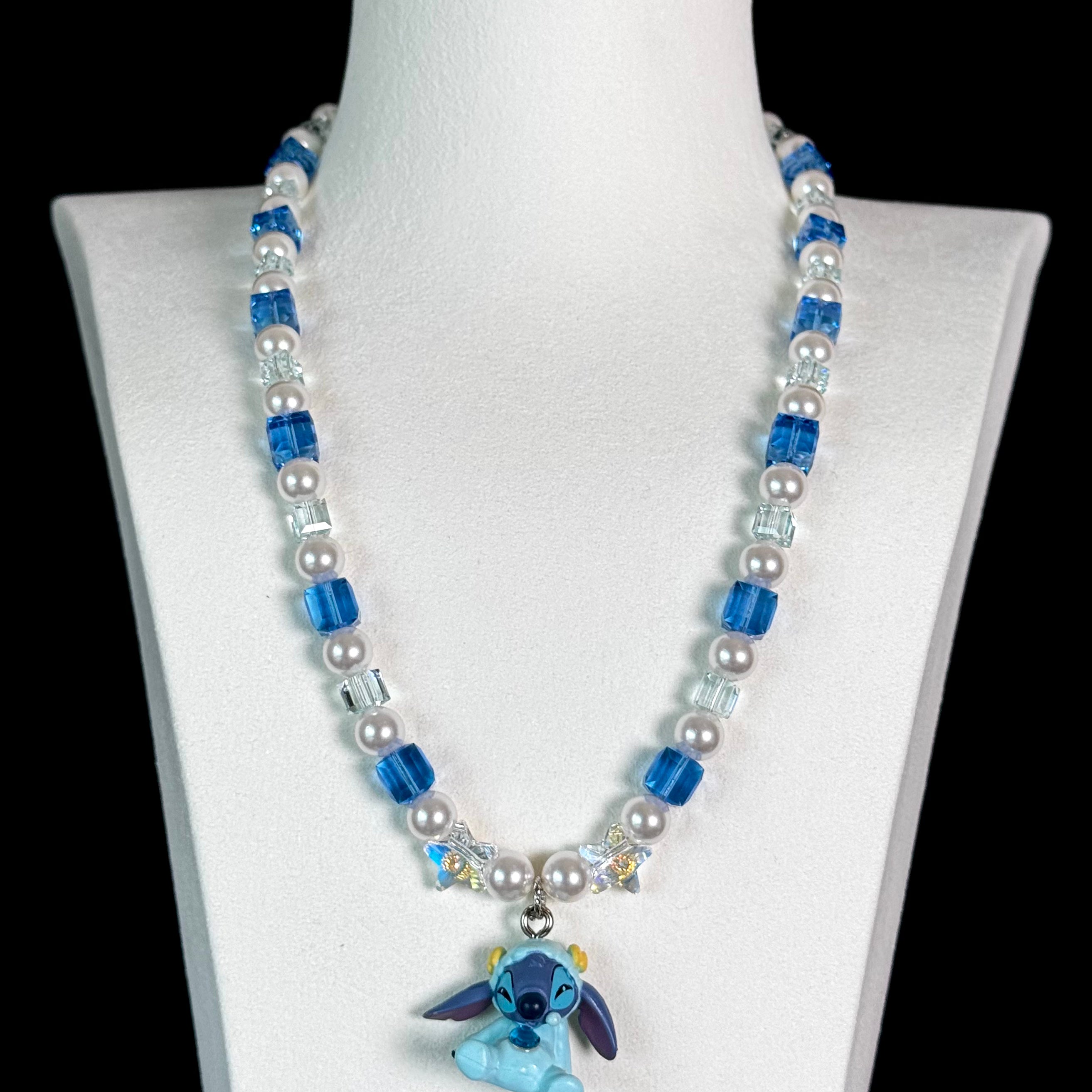 Close-up of a handmade blue Swarovski crystal charm necklace with crystals, pearls and cosmic-inspired collectible charm details