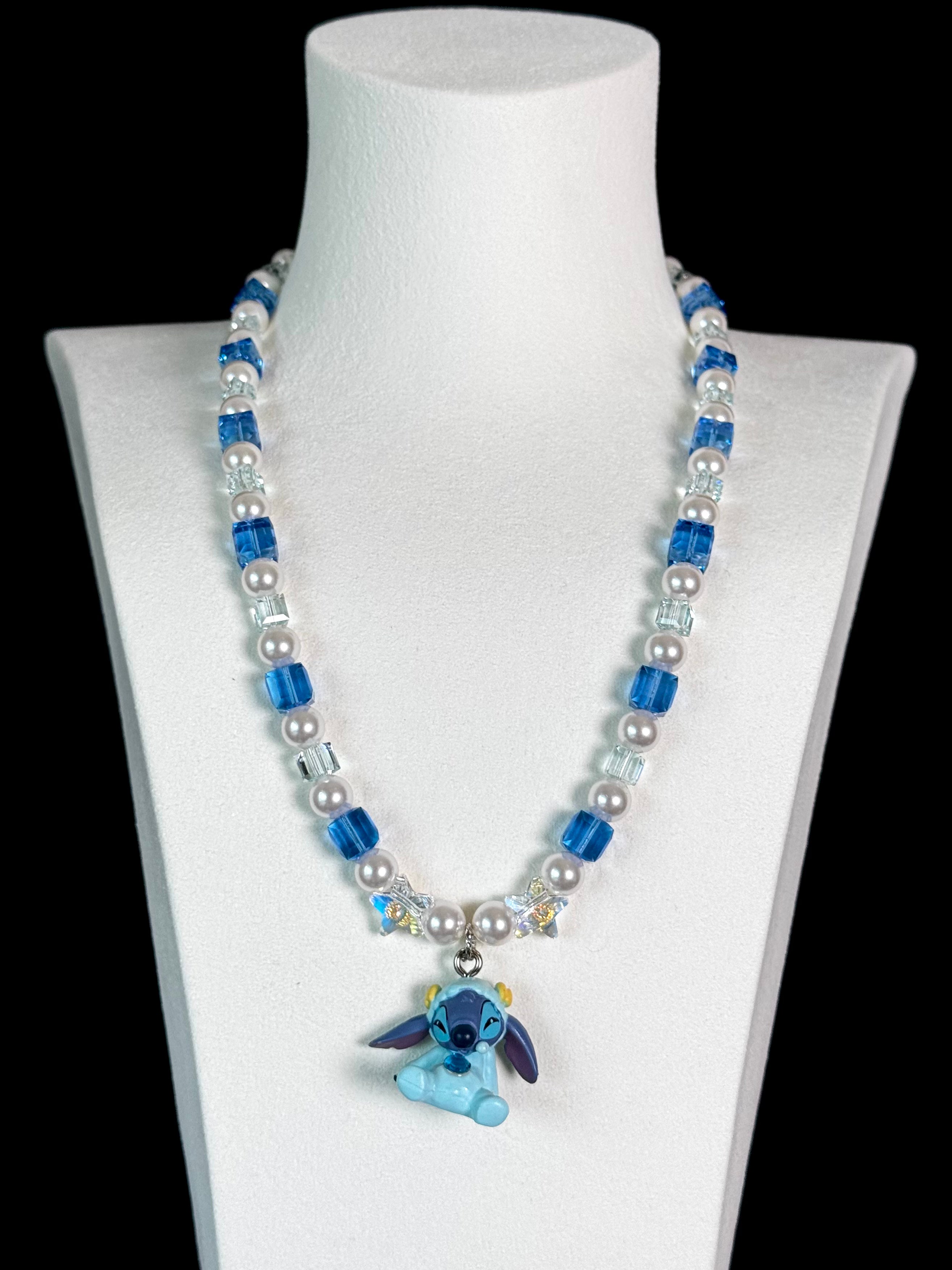 Close-up of a handmade blue Swarovski crystal charm necklace with crystals, pearls and cosmic-inspired collectible charm details