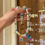 Close-up of a handmade blue Swarovski crystal charm necklace with crystals, pearls and surf-inspired collectible charm details