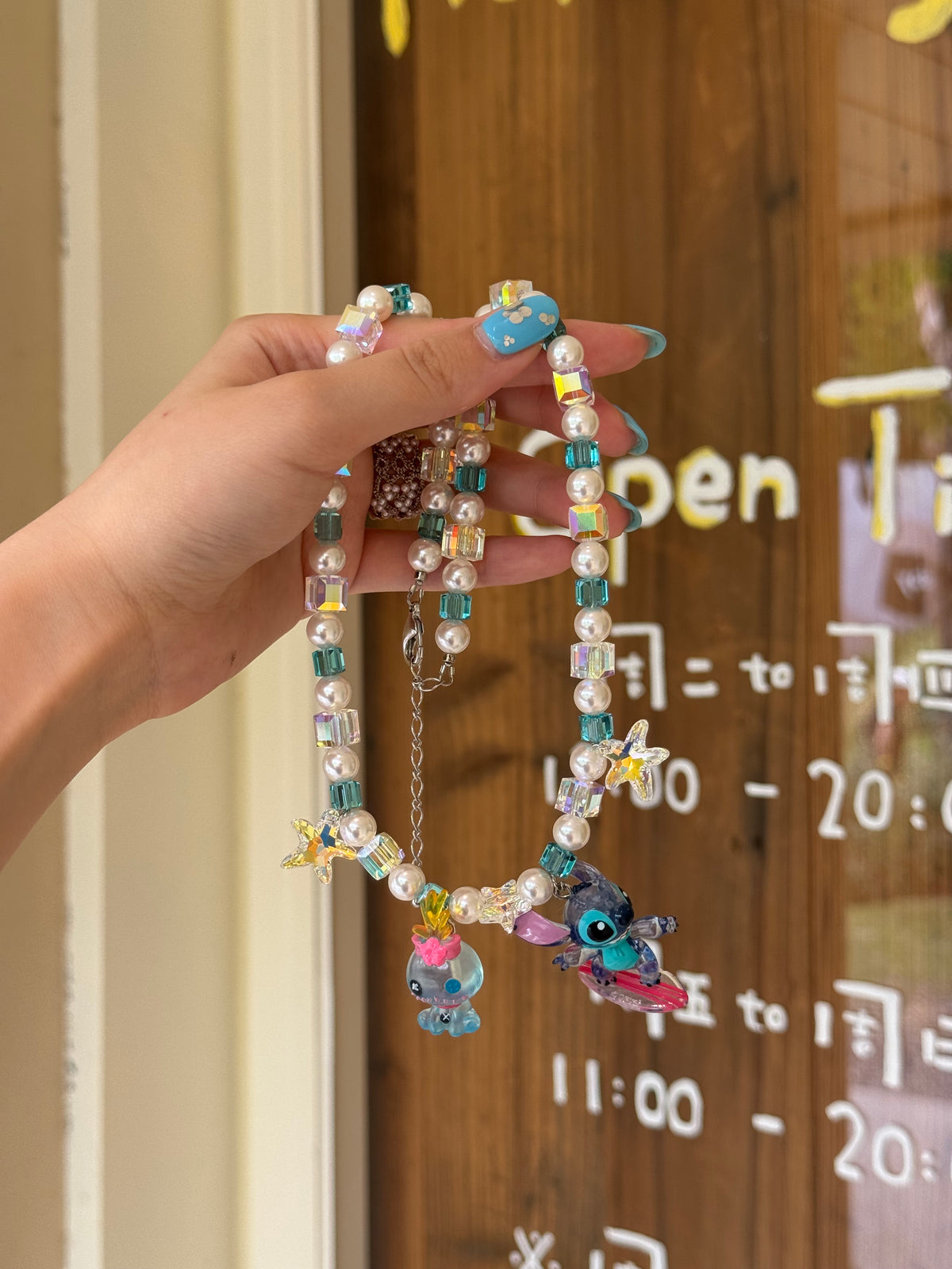 Close-up of a handmade blue Swarovski crystal charm necklace with crystals, pearls and surf-inspired collectible charm details