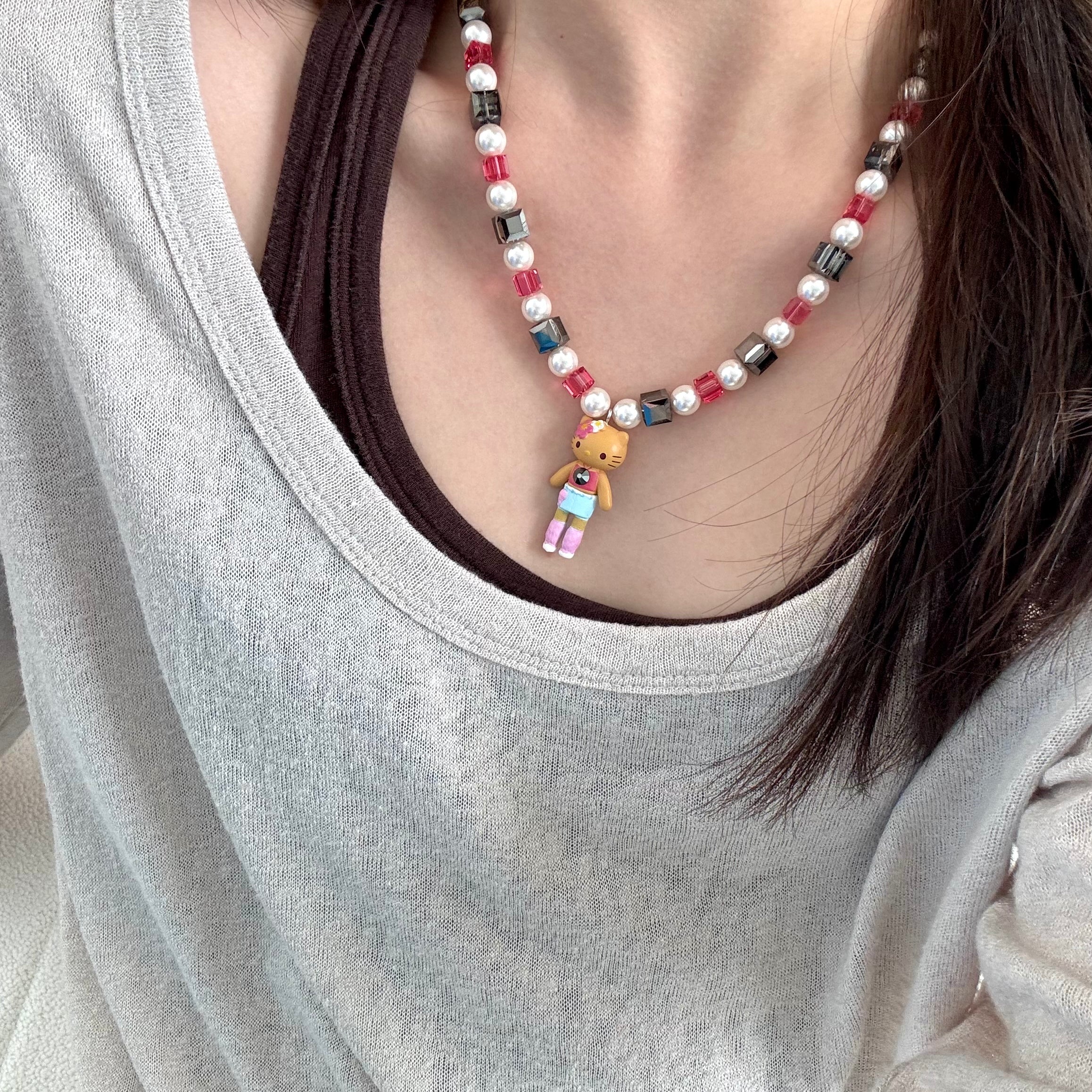 Close-up of a handmade dark Swarovski crystal charm necklace with crystals, pearls and city-inspired collectible charm details