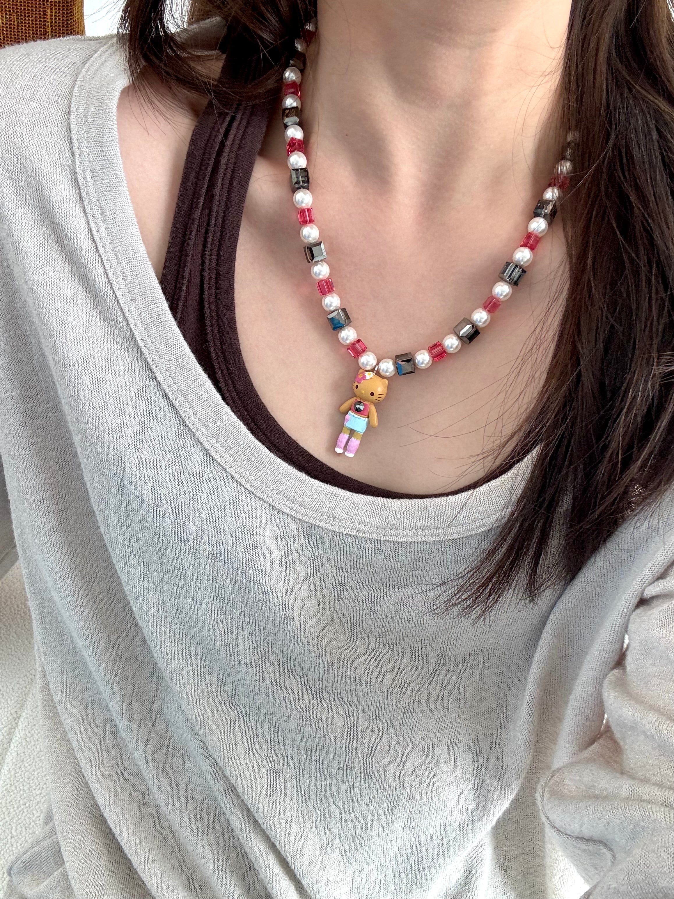 Close-up of a handmade dark Swarovski crystal charm necklace with crystals, pearls and city-inspired collectible charm details