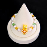 Close-up of a handmade honey citrus Swarovski crystal charm bracelet with crystals, pearls and garden-inspired collectible charm details
