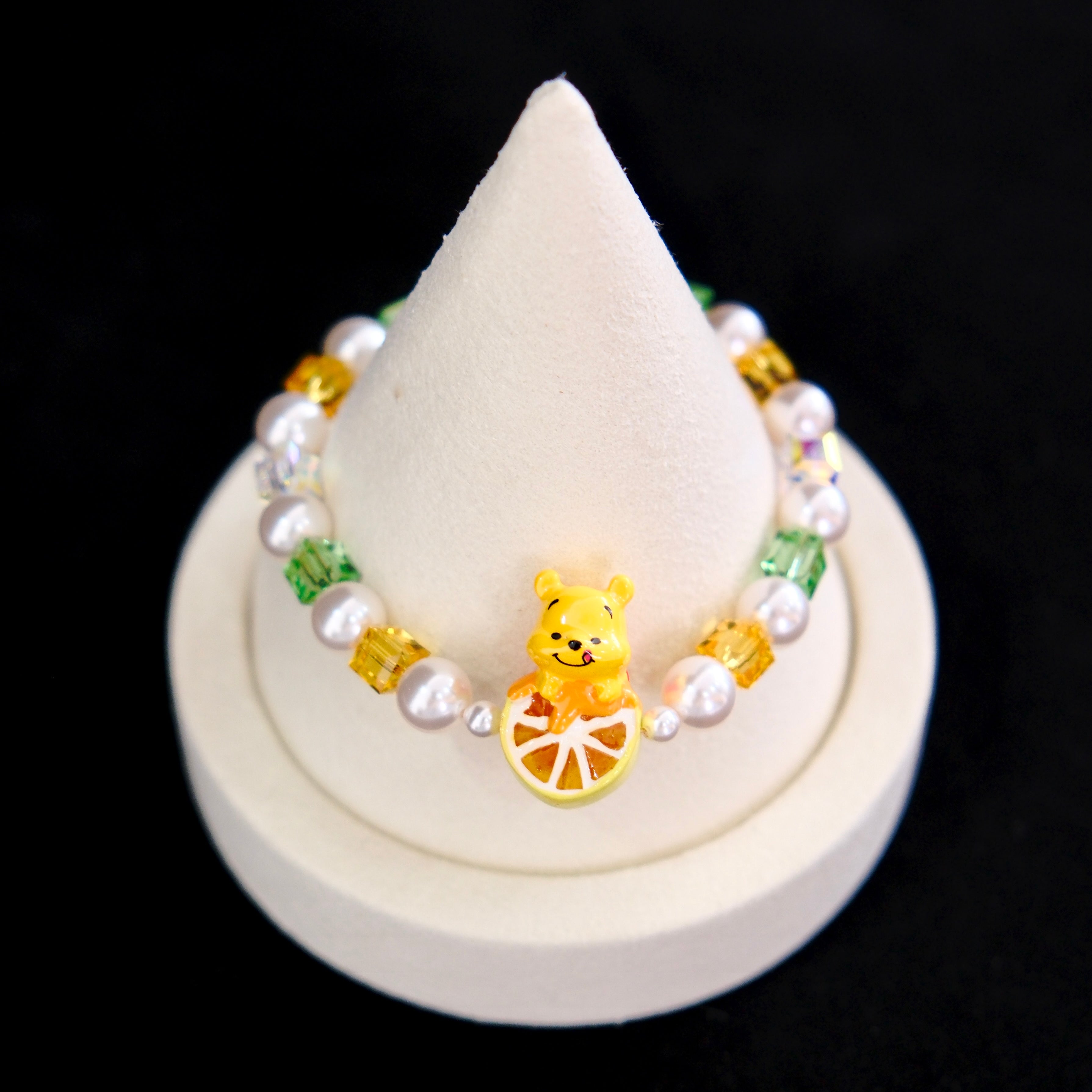 Close-up of a handmade honey citrus Swarovski crystal charm bracelet with crystals, pearls and garden-inspired collectible charm details