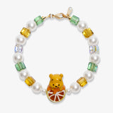Flat lay of a handmade honey citrus Swarovski crystal charm bracelet with crystals, pearls and garden-inspired collectible charm details