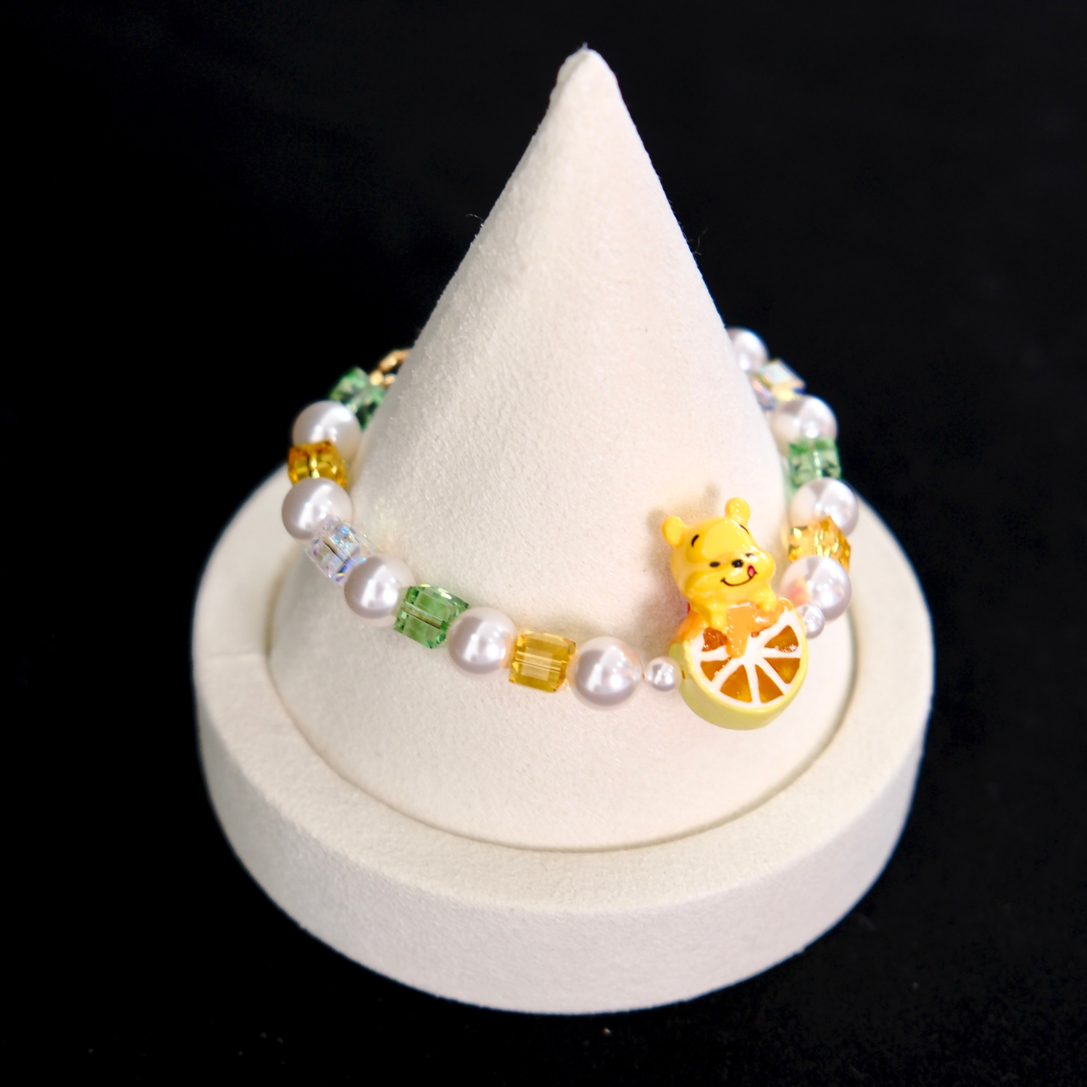 Side view of a handmade honey citrus Swarovski crystal charm bracelet with layered crystals, pearls and garden-inspired collectible charm details