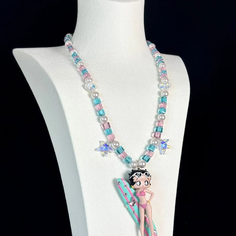 Close-up of a handmade pink Swarovski crystal charm necklace with crystals, pearls and surf-inspired collectible charm details