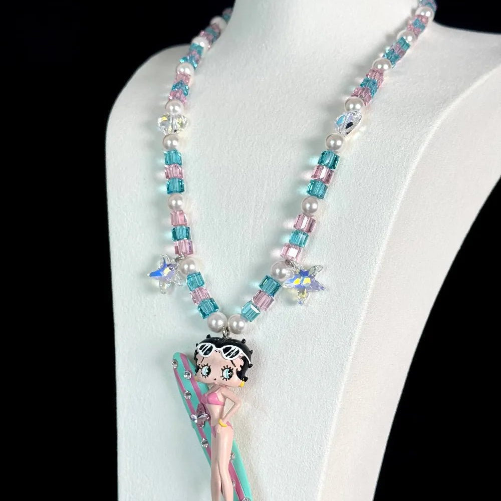 Close-up of a handmade pink Swarovski crystal charm necklace with crystals, pearls and surf-inspired collectible charm details