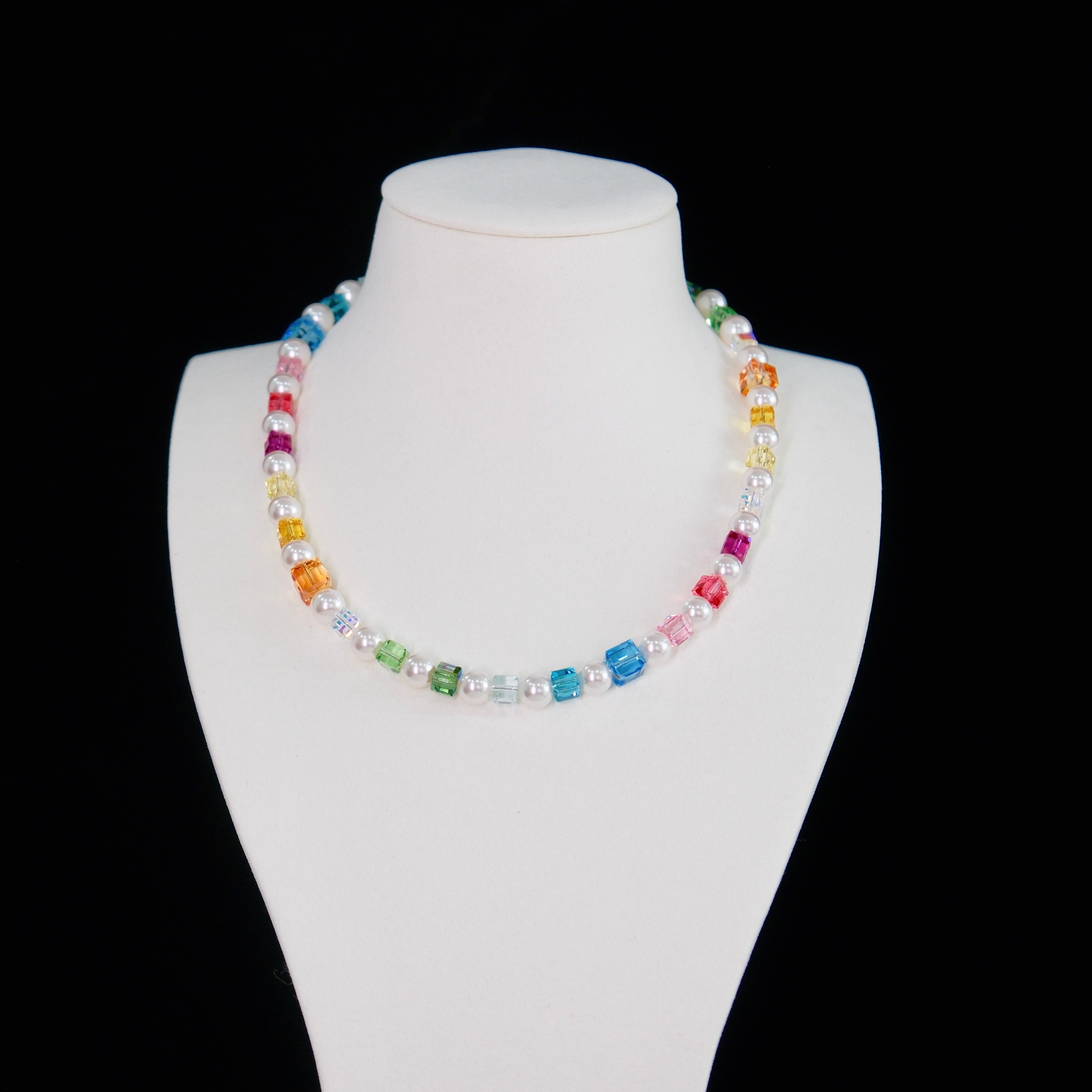 Close-up of a handmade rainbow Swarovski crystal charm necklace with crystals, pearls and rainbow-inspired collectible charm details