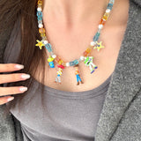 Model wearing a handmade Swarovski crystal charm necklace with crystals, pearls and rainbow-inspired collectible charm details
