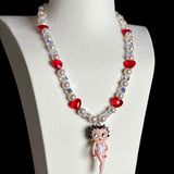 Close-up of a handmade red Swarovski crystal charm necklace with crystals, pearls and retro-inspired collectible charm details