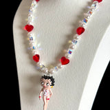 Close-up of a handmade red Swarovski crystal charm necklace with crystals, pearls and retro-inspired collectible charm details