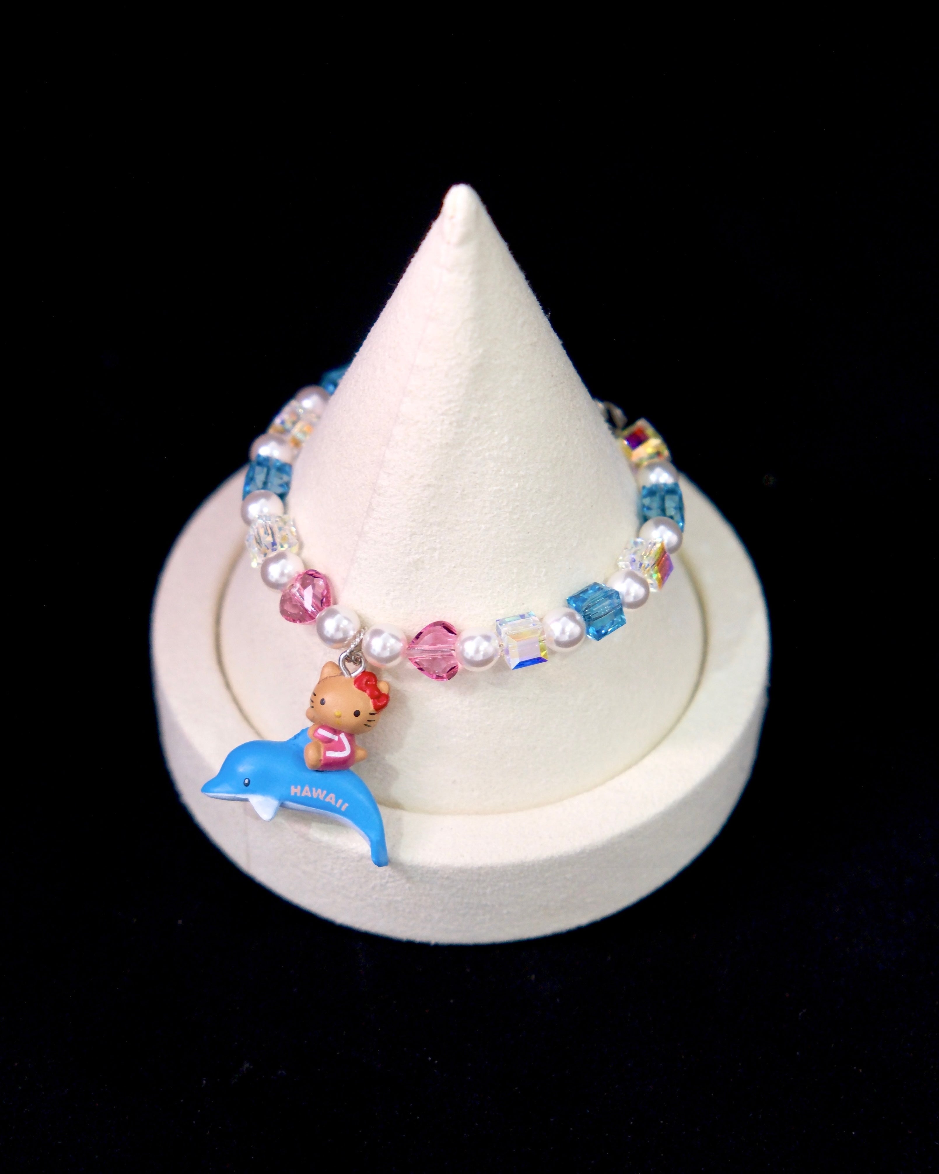 Side view of a handmade Swarovski crystal charm bracelet with layered crystals, pearls and surf-inspired collectible charm details