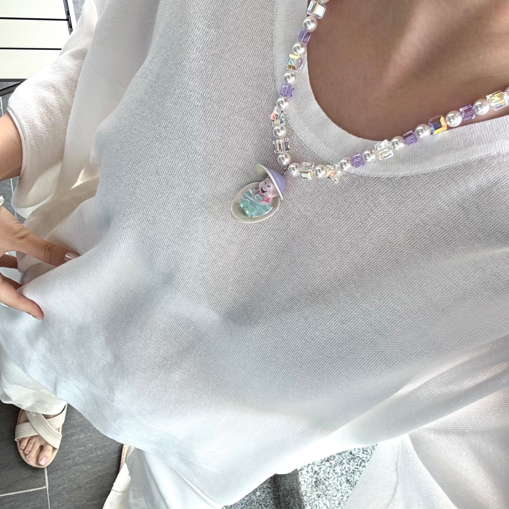 Close-up of a handmade Swarovski crystal charm necklace with crystals, pearls and surf-inspired collectible charm details