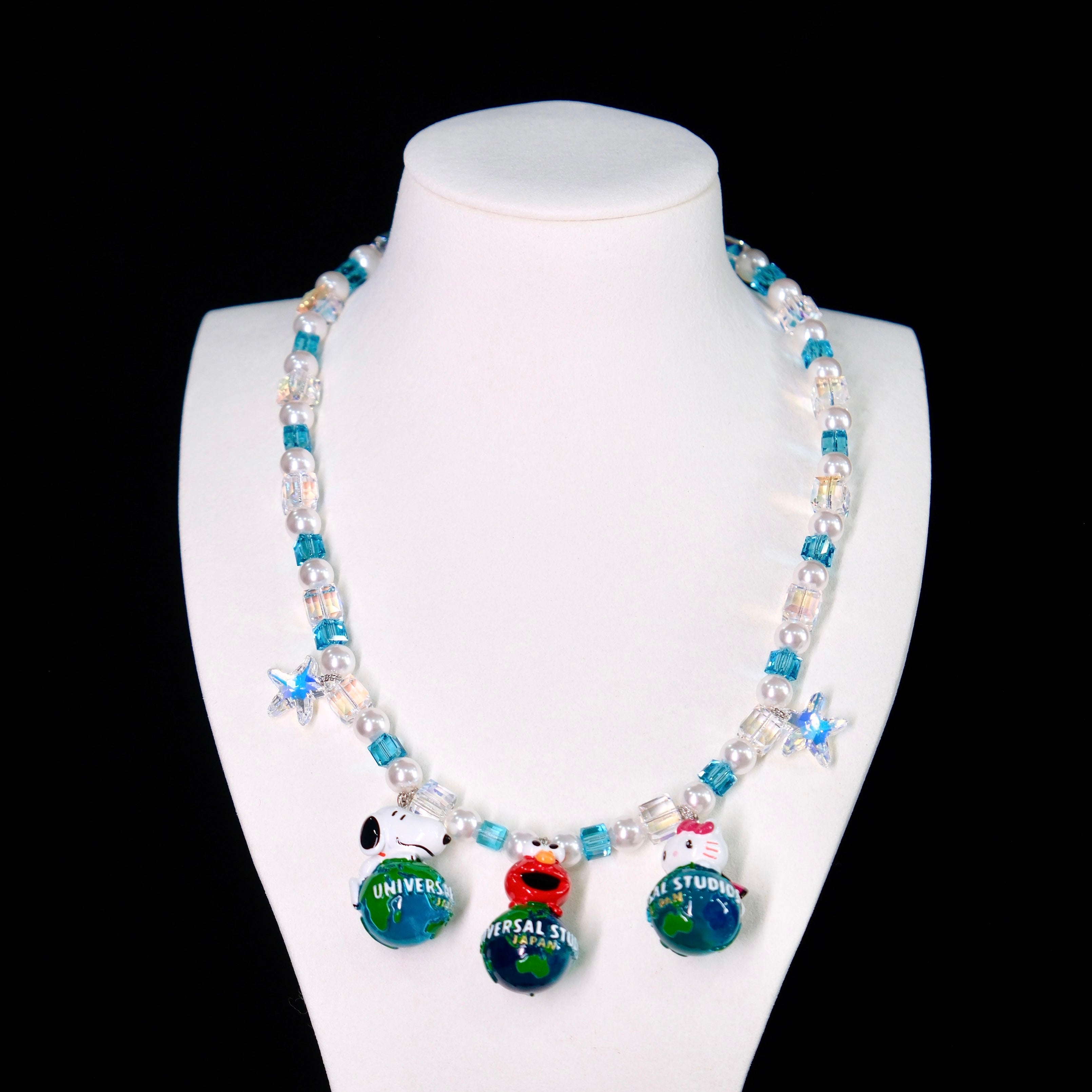 Close-up of a handmade Swarovski crystal charm necklace with crystals, pearls and travel-inspired collectible charm details