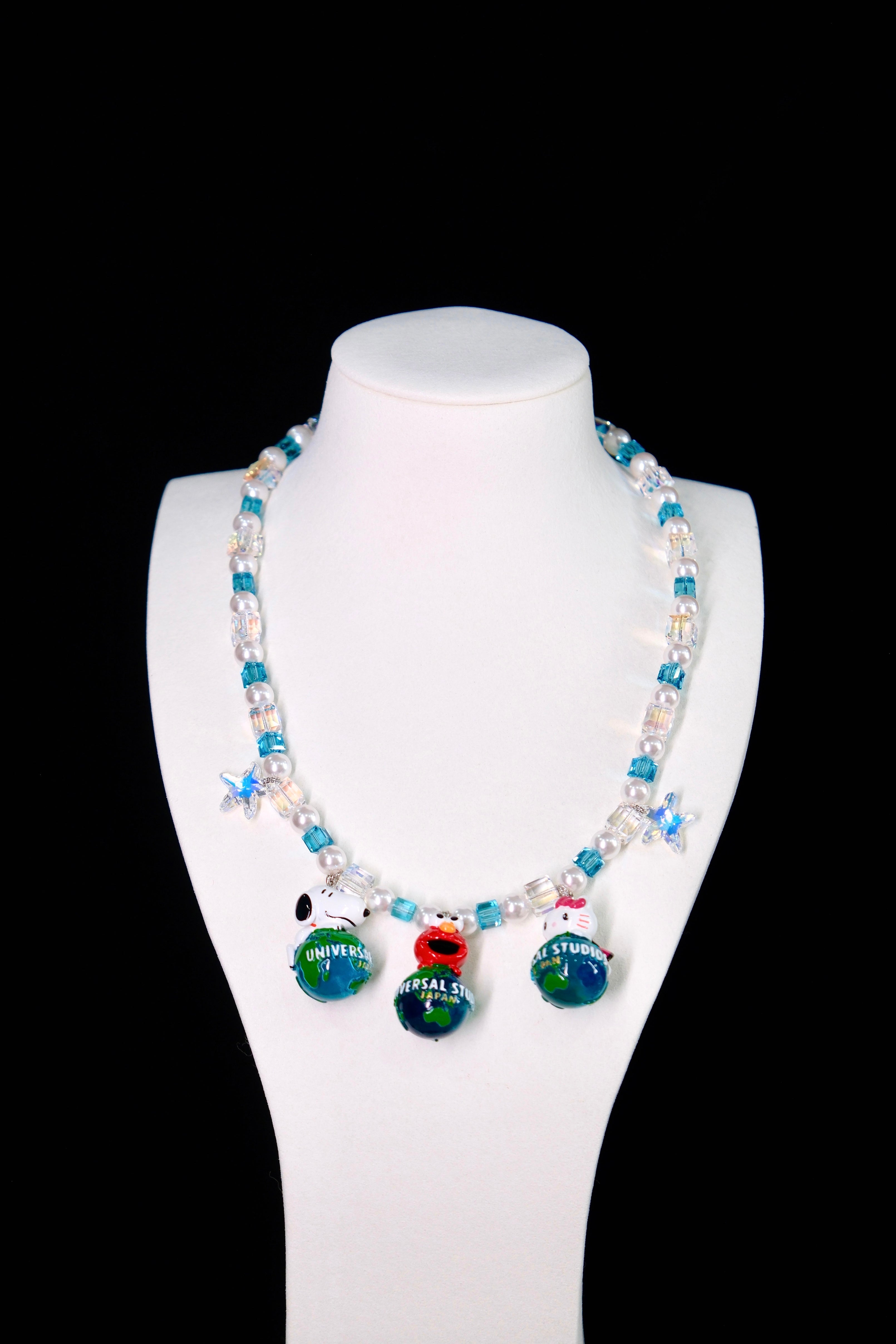 Close-up of a handmade Swarovski crystal charm necklace with crystals, pearls and travel-inspired collectible charm details