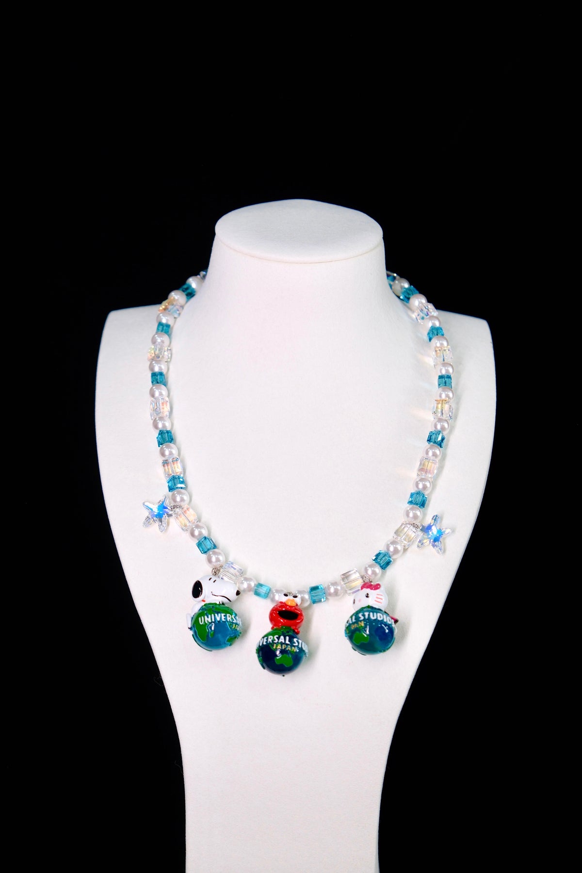 Close-up of a handmade Swarovski crystal charm necklace with crystals, pearls and travel-inspired collectible charm details