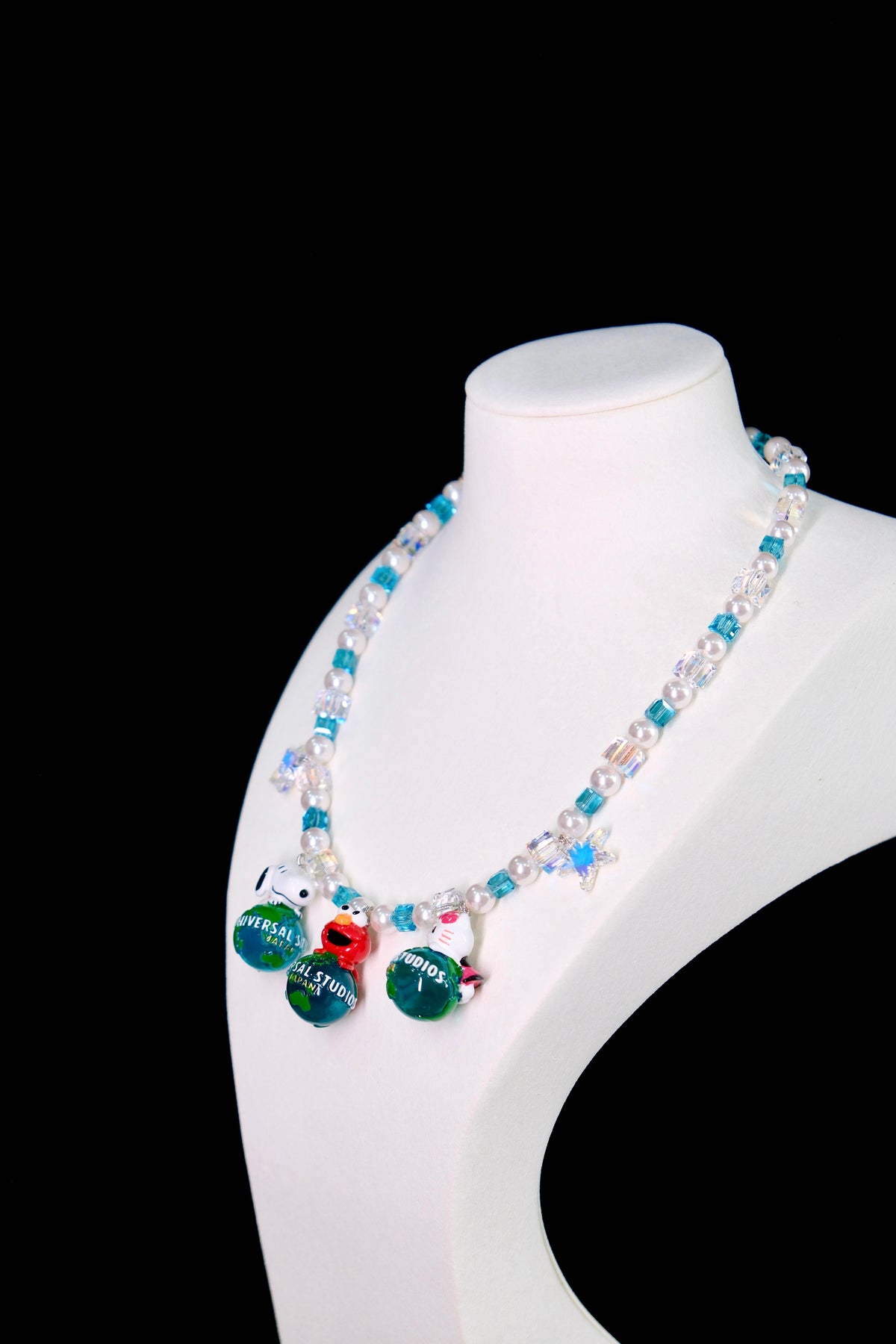 Model wearing a handmade Swarovski crystal charm necklace with crystals, pearls and travel-inspired collectible charm details