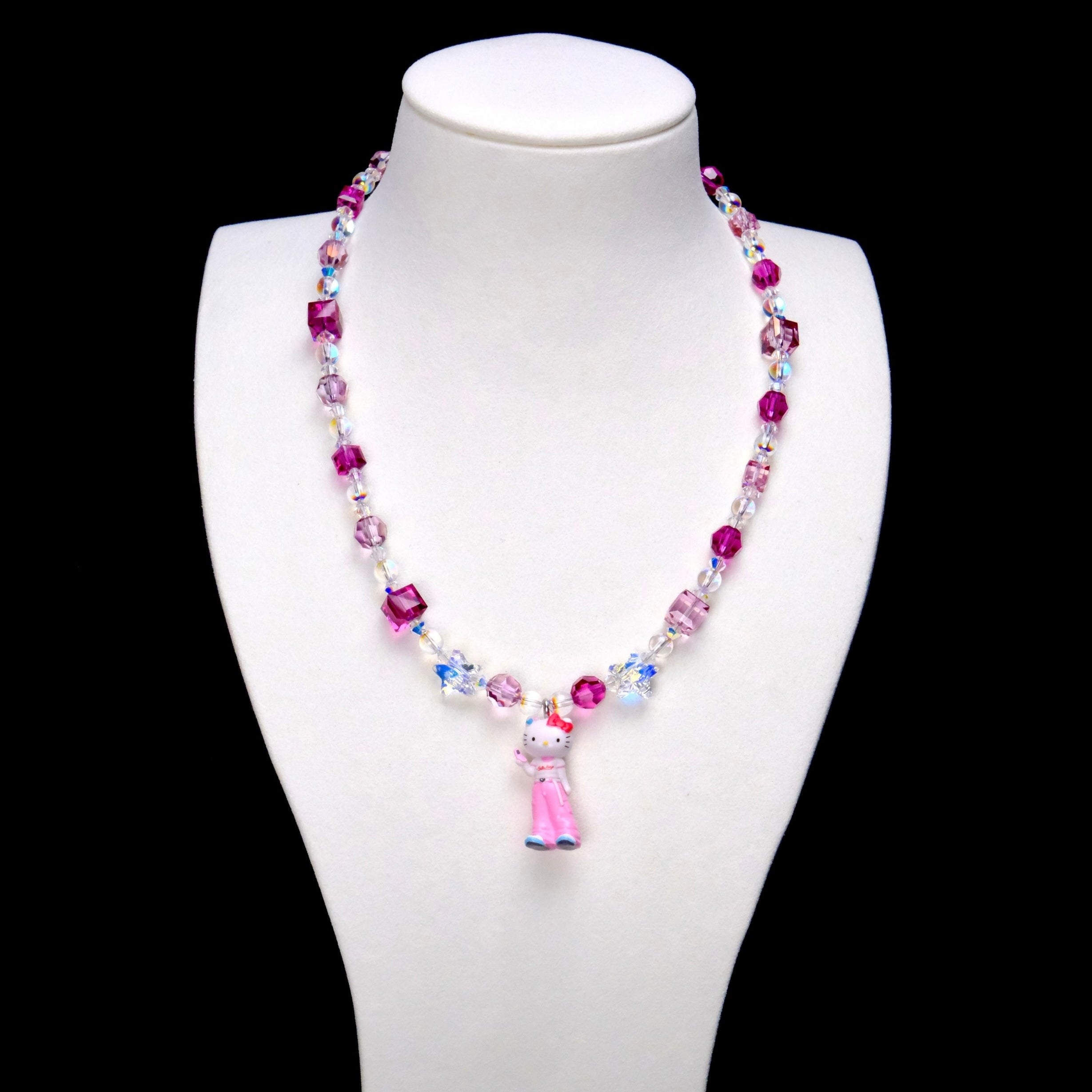 Pink crystal rounds and cubes alternate with clear iridescent beads. Clear star accents frame a Hello Kitty charm in pink trousers with blue shoes.