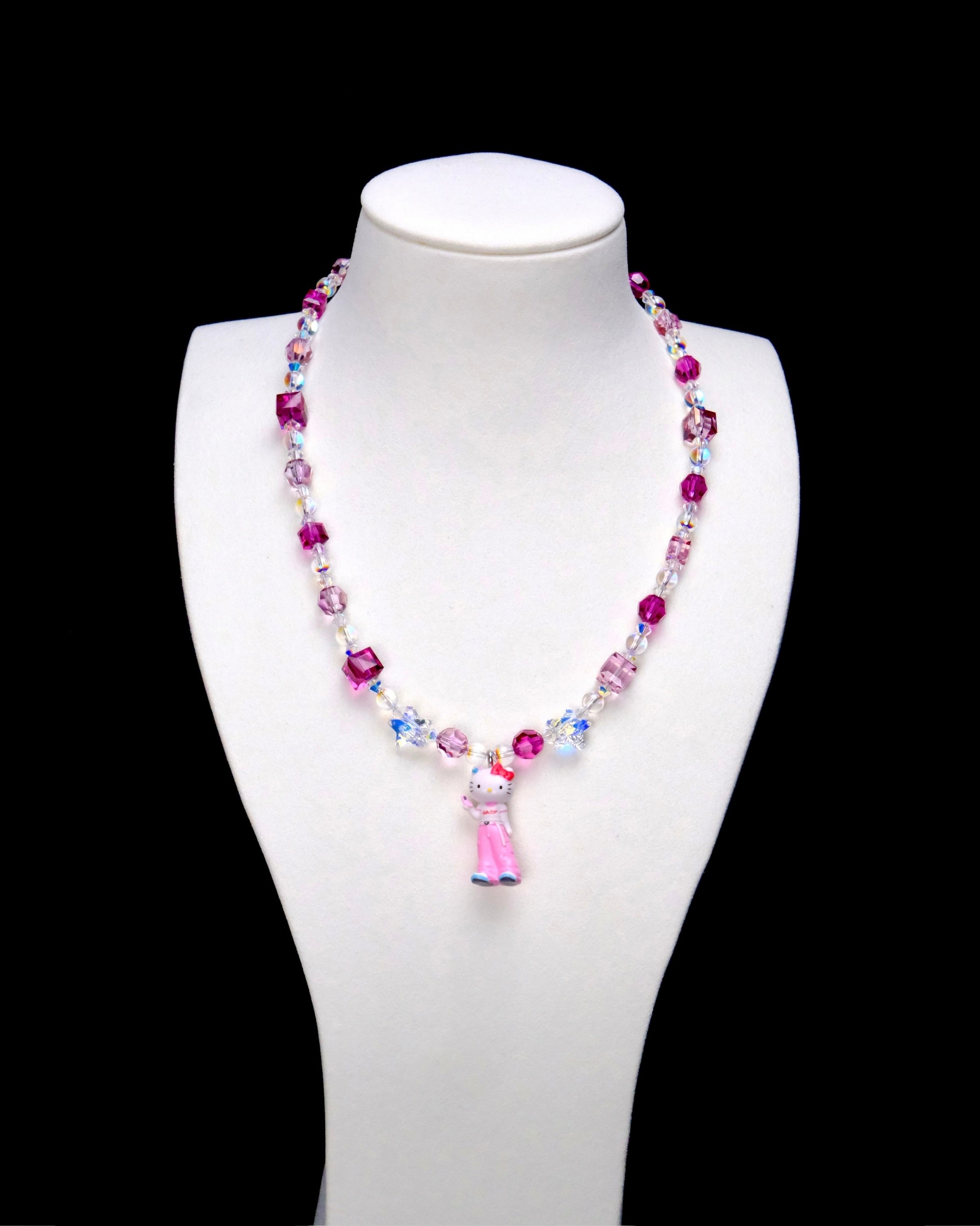 Pink crystal rounds and cubes alternate with clear iridescent beads. Clear star accents frame a Hello Kitty charm in pink trousers with blue shoes.