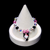 Pink, black and clear iridescent crystal rounds with small white pearl beads frame a pink crystal bow and a Hello Kitty charm wearing a black animal hood with a pink snout.