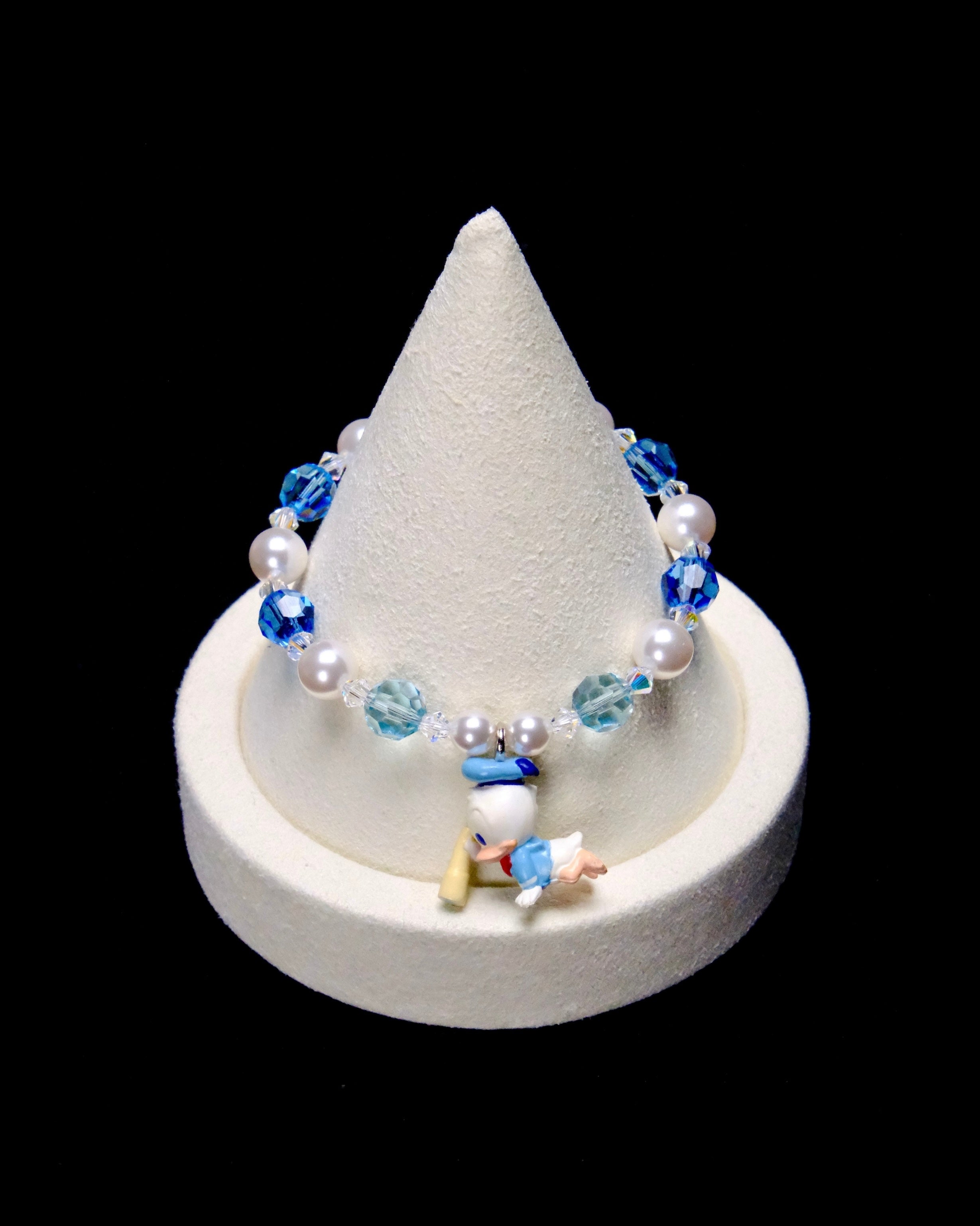 Deep blue and pale aqua crystal rounds alternate with white pearl beads and clear spacers, framing a little Donald Duck charm in a light blue sailor outfit.