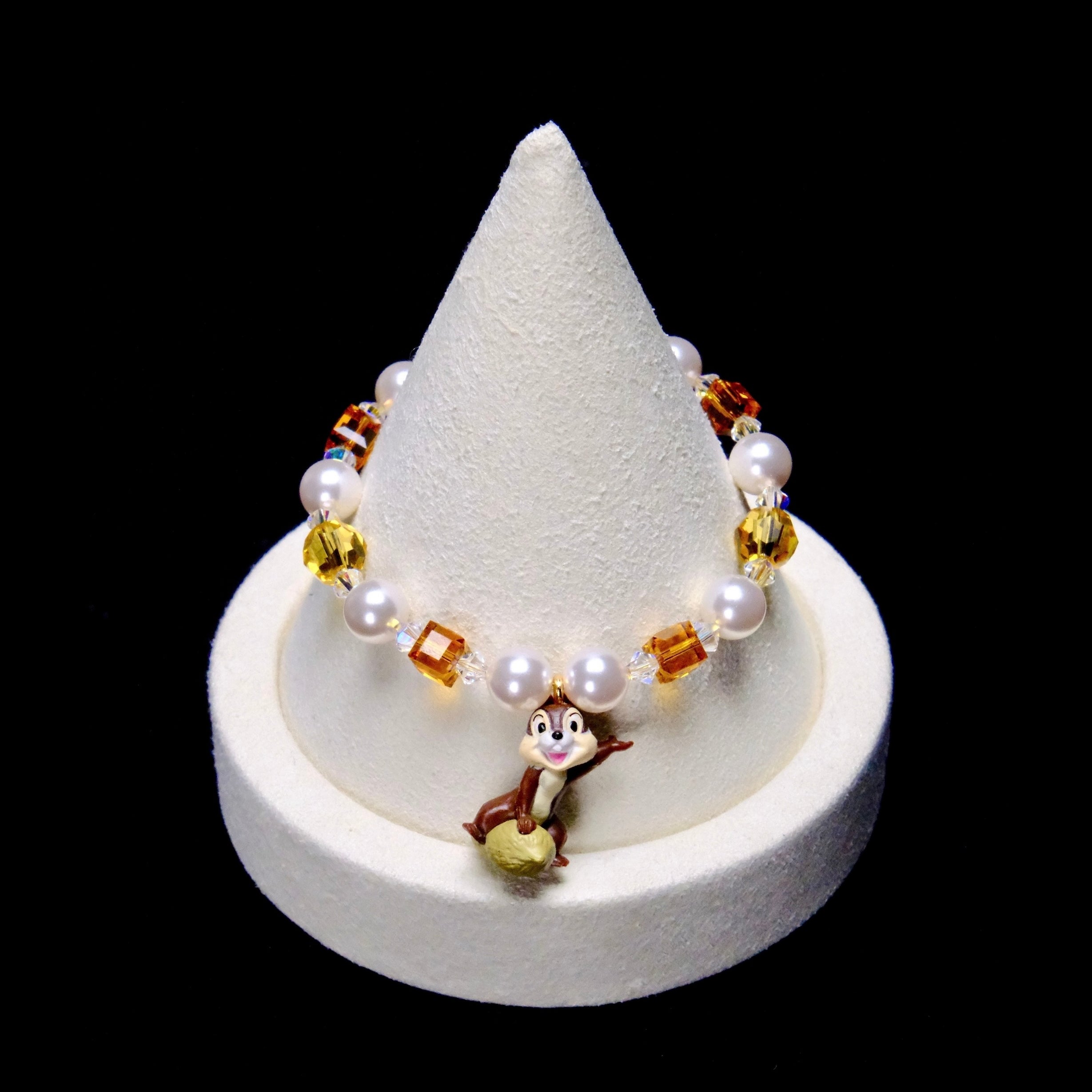 Amber crystal cubes, yellow crystal rounds and white pearl beads frame a smiling chipmunk charm perched on a nut.