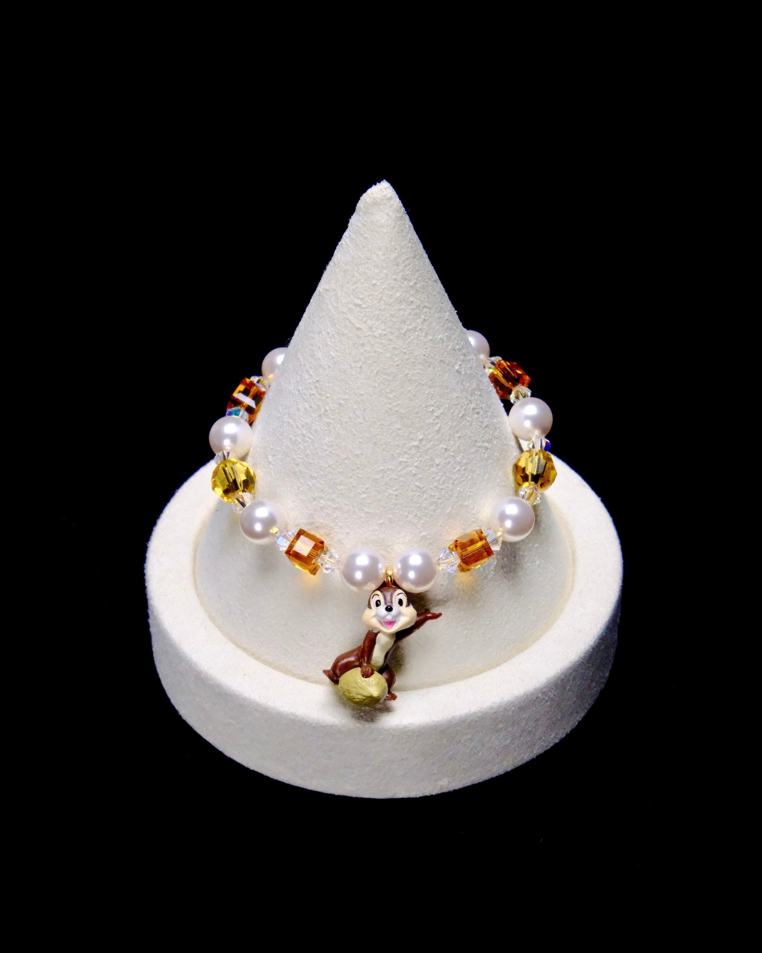 Amber crystal cubes, yellow crystal rounds and white pearl beads frame a smiling chipmunk charm perched on a nut.