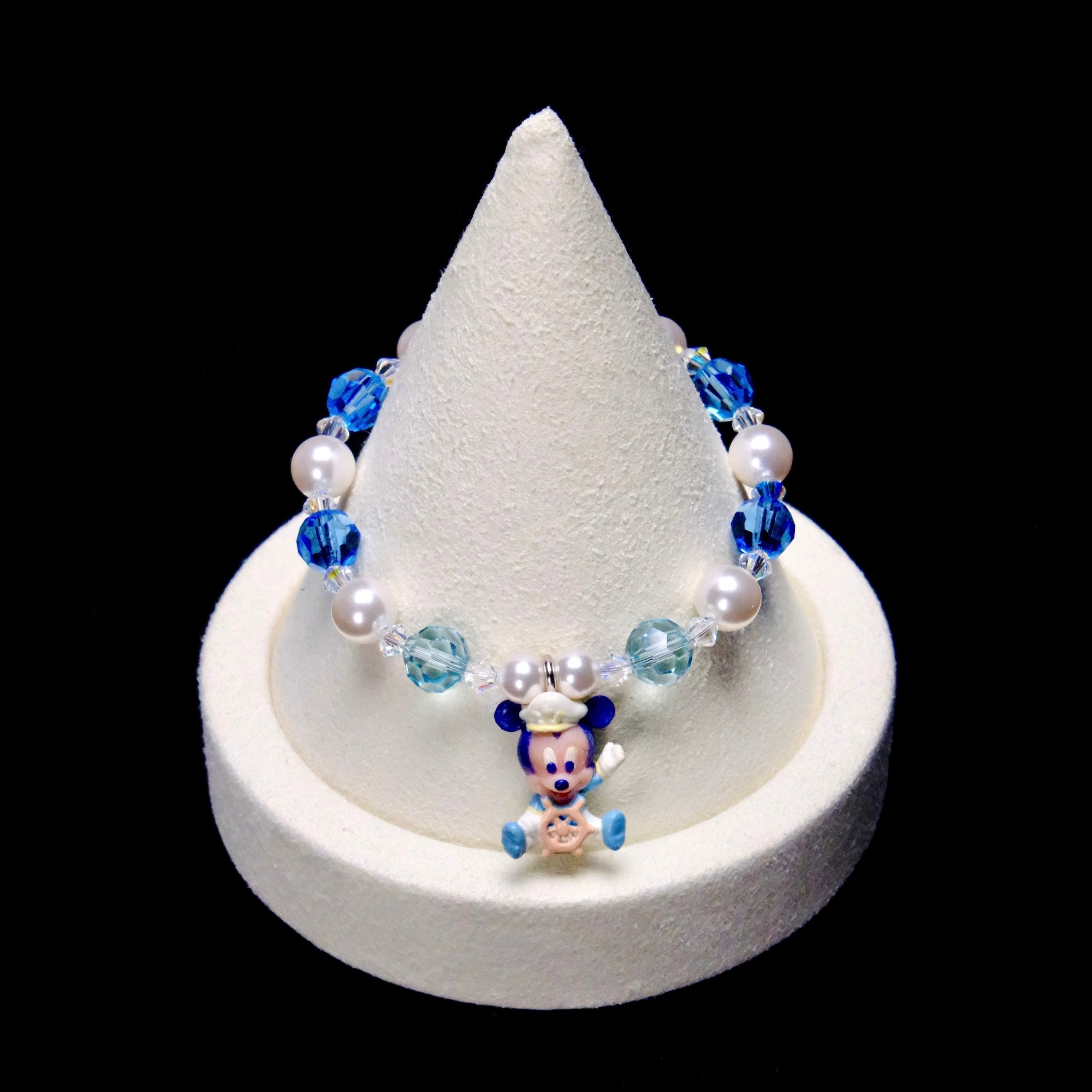 Blue and pale aqua crystal rounds, white pearl beads and clear spacers frame a little Mickey Mouse charm wearing a captain's hat and holding a ship's wheel.