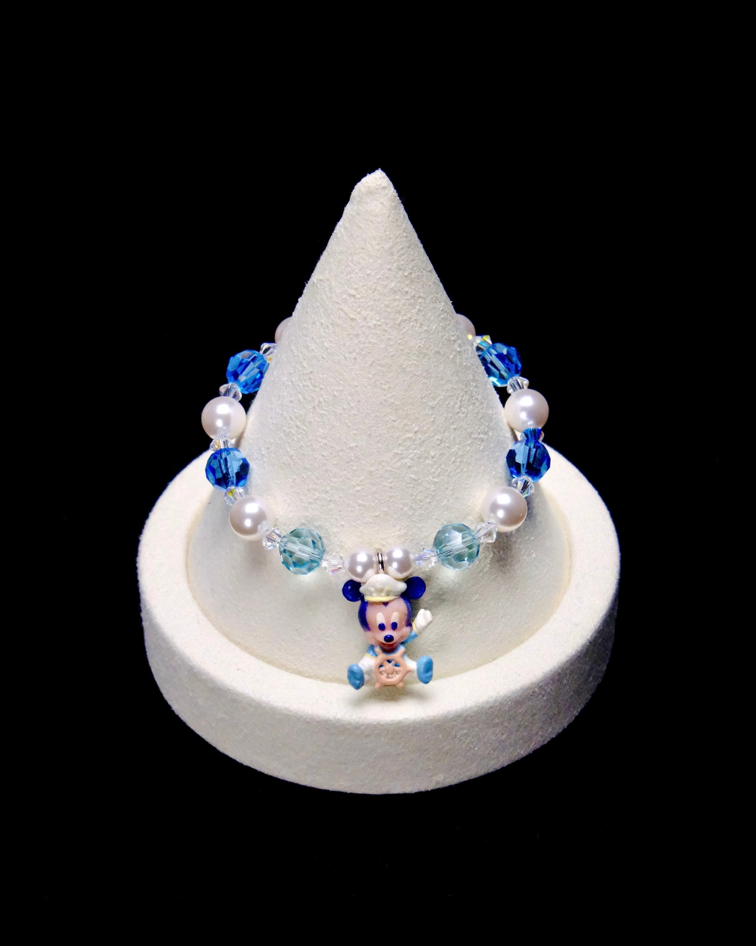 Blue and pale aqua crystal rounds, white pearl beads and clear spacers frame a little Mickey Mouse charm wearing a captain's hat and holding a ship's wheel.