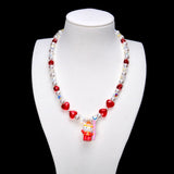 Red crystal rounds and four red hearts pair with white pearl beads and iridescent crystal cubes. A Hello Kitty charm in a red winter outfit holds a pink board.