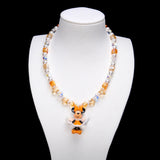 Amber and champagne crystal cubes, golden star accents and white pearl beads frame Minnie Mouse in an orange bow and orange-and-white outfit.