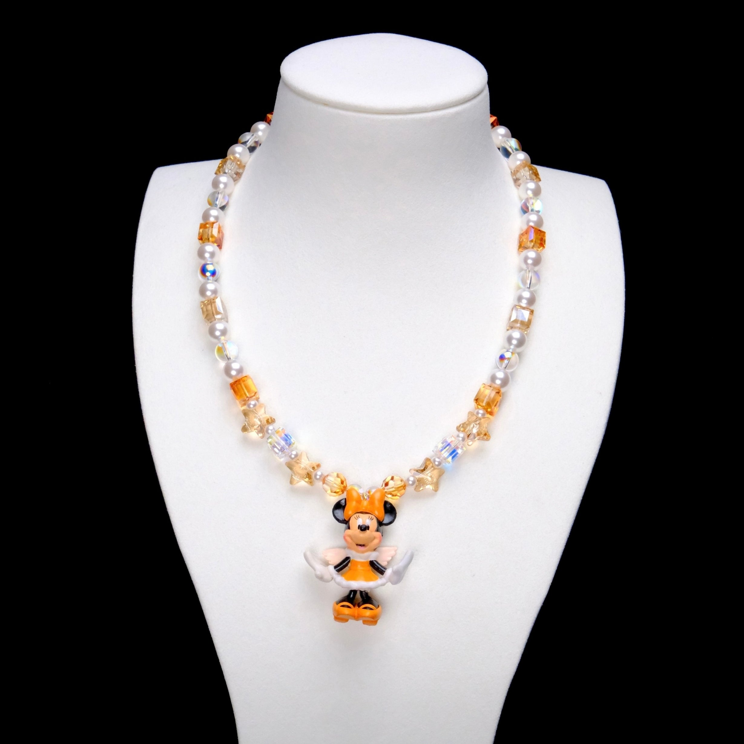 Amber and champagne crystal cubes, golden star accents and white pearl beads frame Minnie Mouse in an orange bow and orange-and-white outfit.