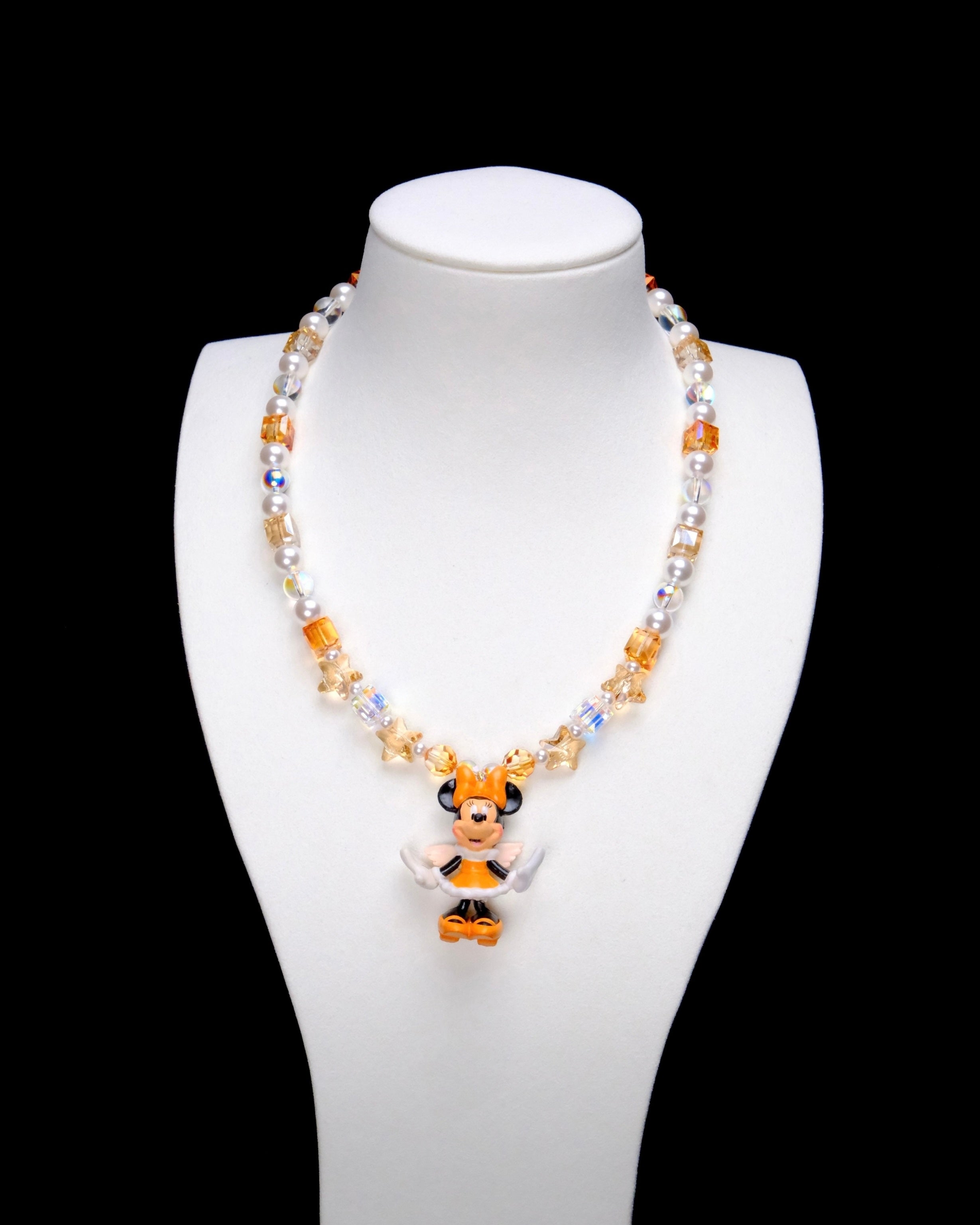 Amber and champagne crystal cubes, golden star accents and white pearl beads frame Minnie Mouse in an orange bow and orange-and-white outfit.
