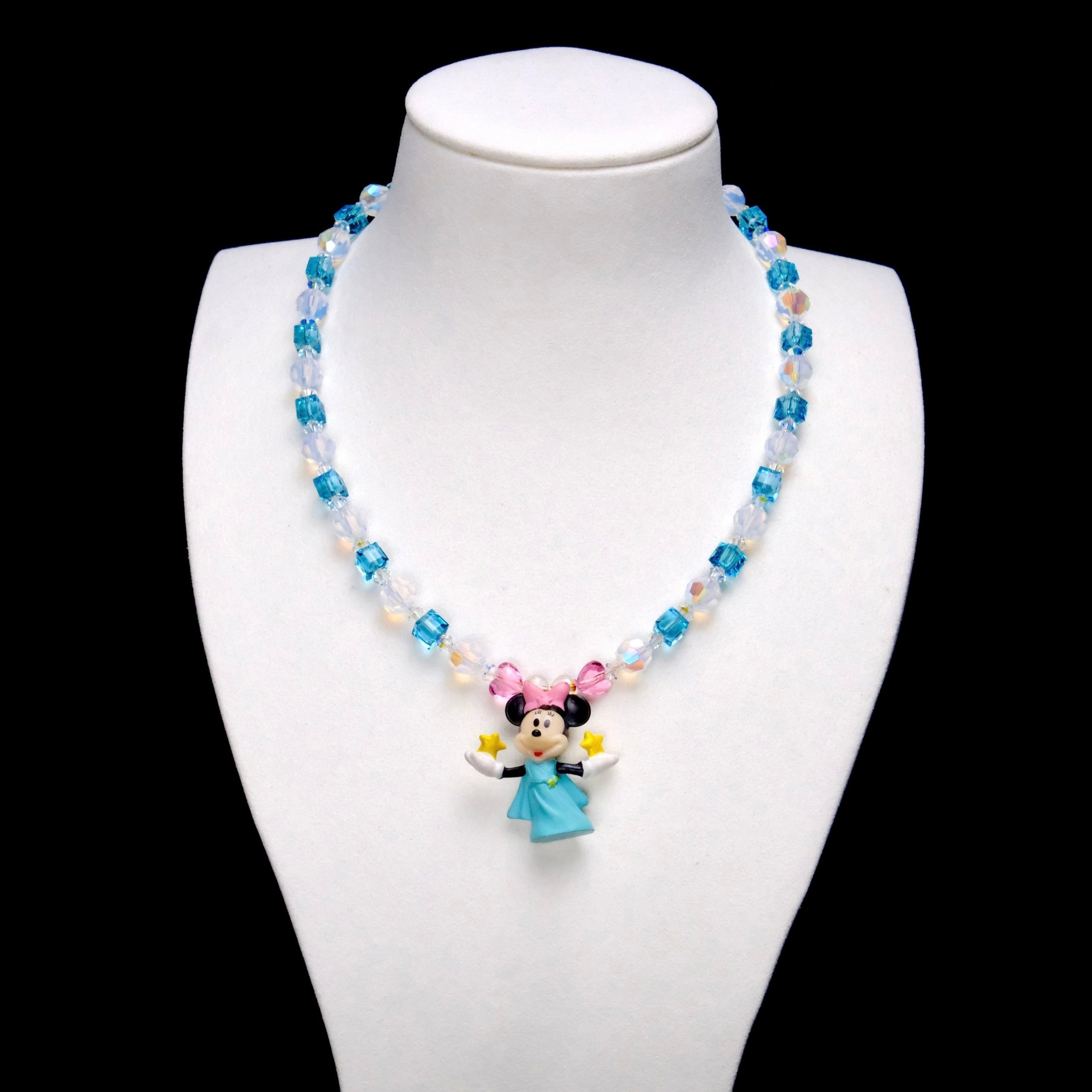 Aqua crystal cubes and pale iridescent rounds lead to pink crystal accents and a Minnie Mouse charm wearing a blue dress and pink bow, with yellow stars in her hands.