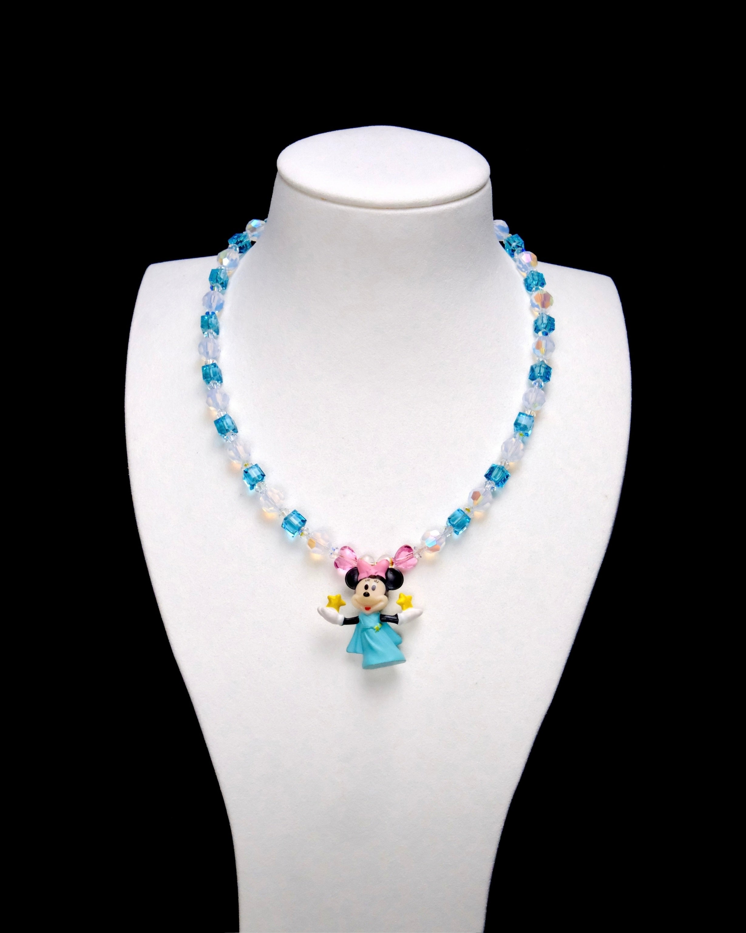 Aqua crystal cubes and pale iridescent rounds lead to pink crystal accents and a Minnie Mouse charm wearing a blue dress and pink bow, with yellow stars in her hands.